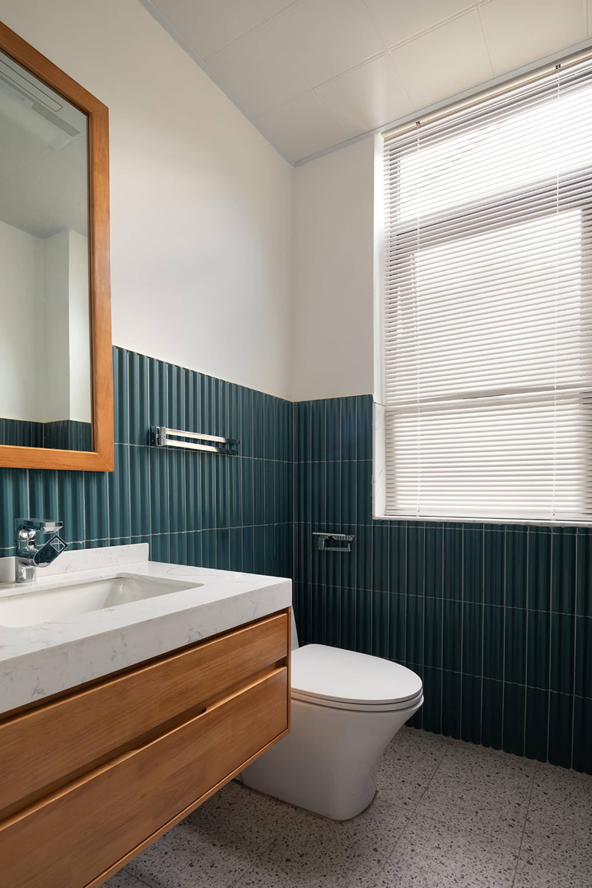 Modern bathroom interior with green tiles and wooden vanity.