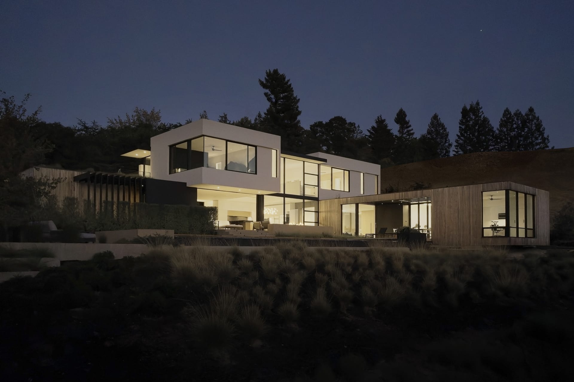 A modern house featuring a contemporary design with wooden accents, glass walls, and concrete structures.