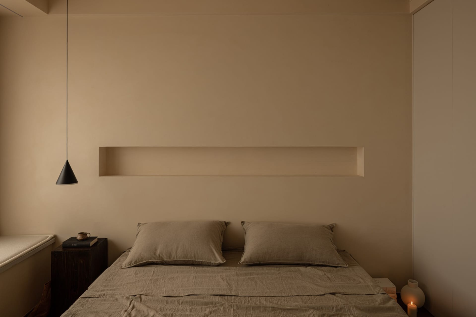 A minimalist bedroom with concrete walls and wooden bed frame.