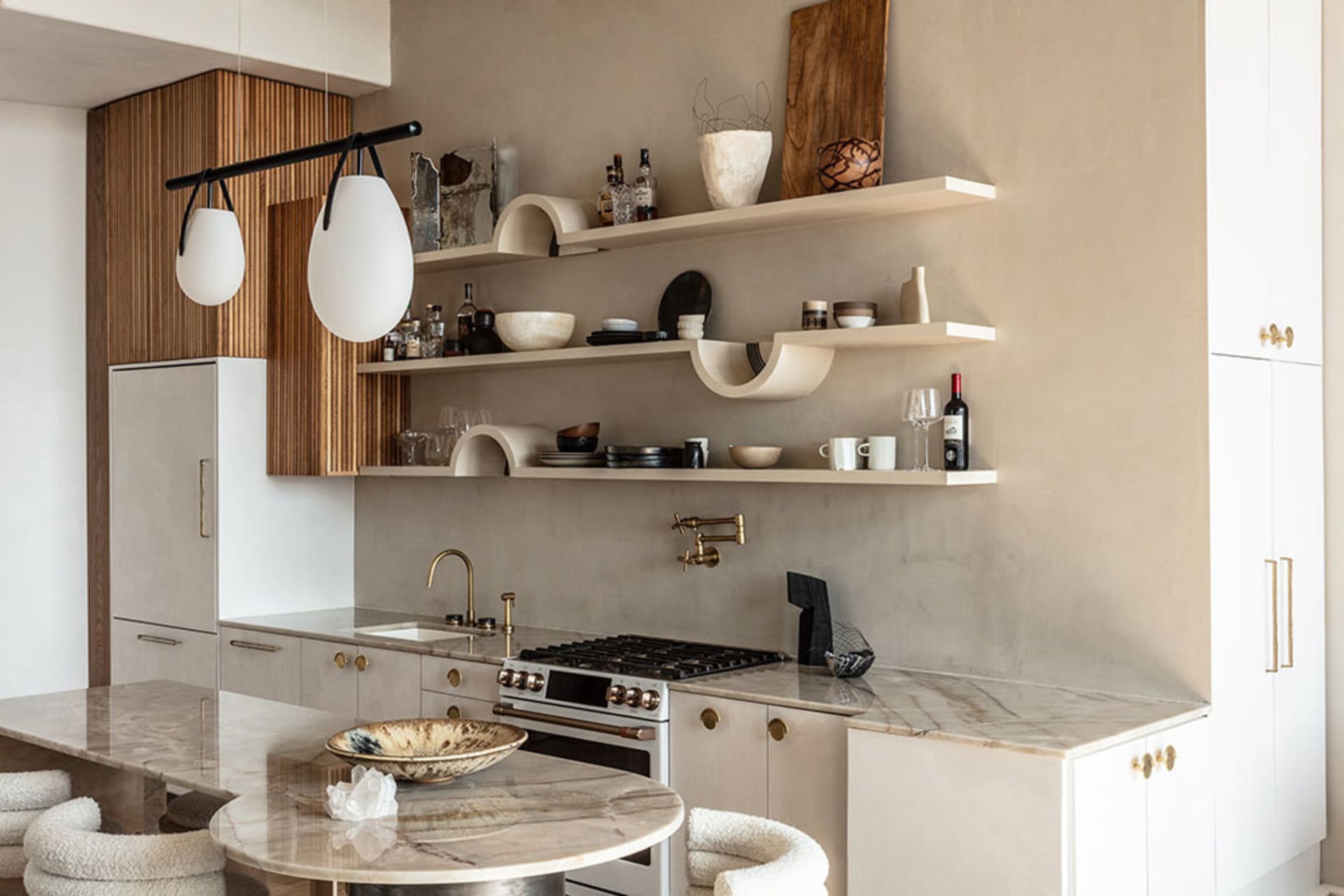 A modern kitchen with white marble countertops and shelves filled with various decorative items and kitchenware.