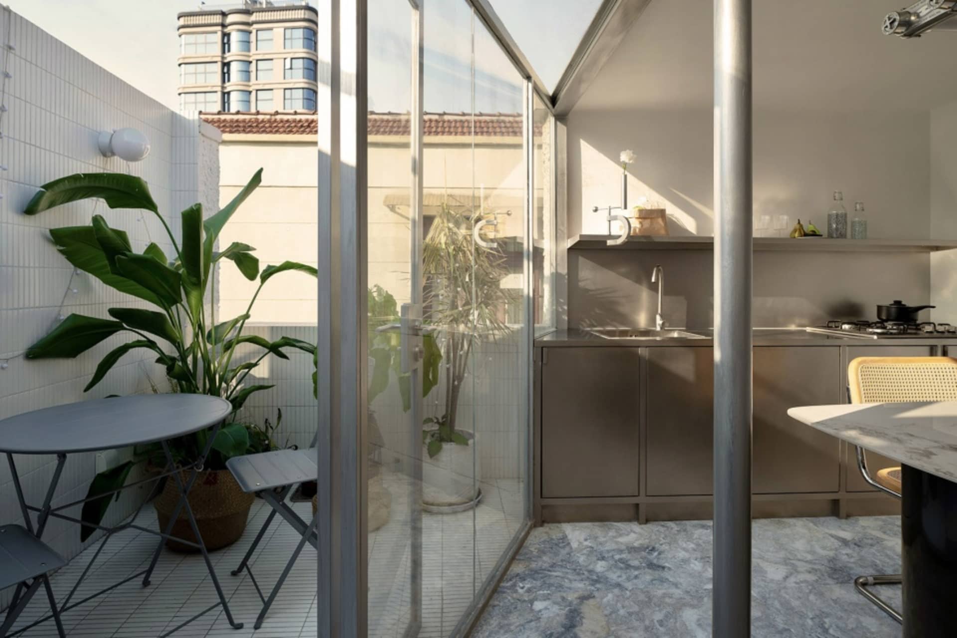 An apartment balcony featuring a glass enclosure, plants, and modern furniture.