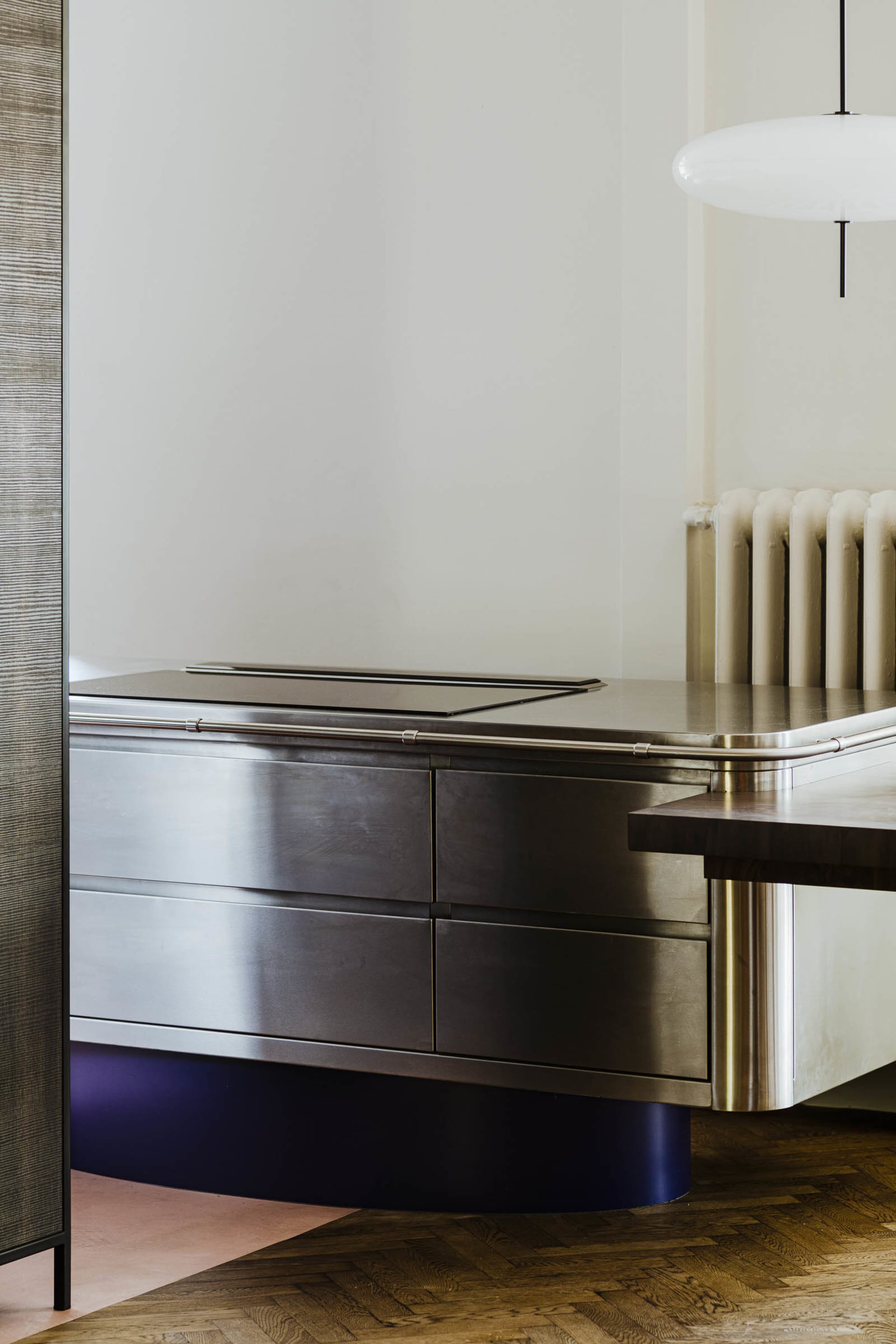 A minimalist interior with a metallic counter featuring sleek drawers and a smooth, curved base.