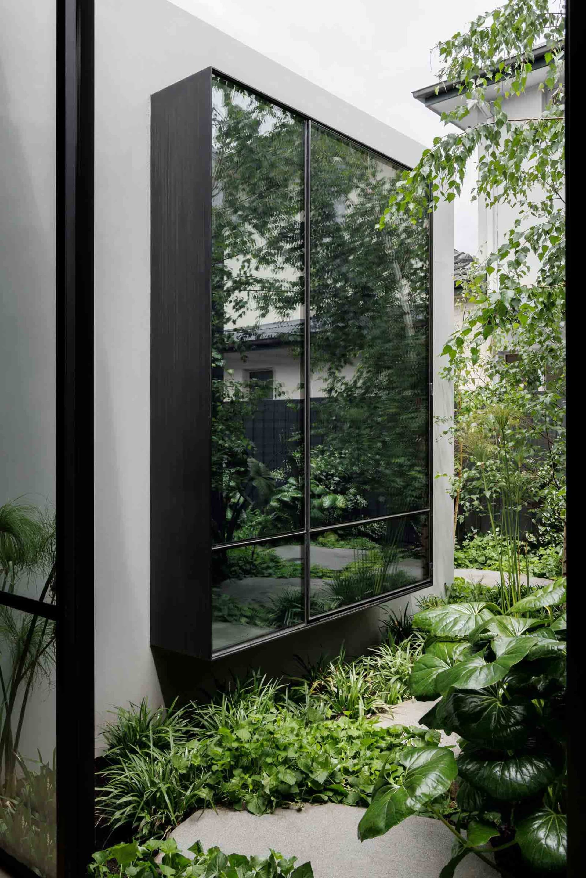 Modern exterior design featuring glass walls and steel framing with a garden house extension.