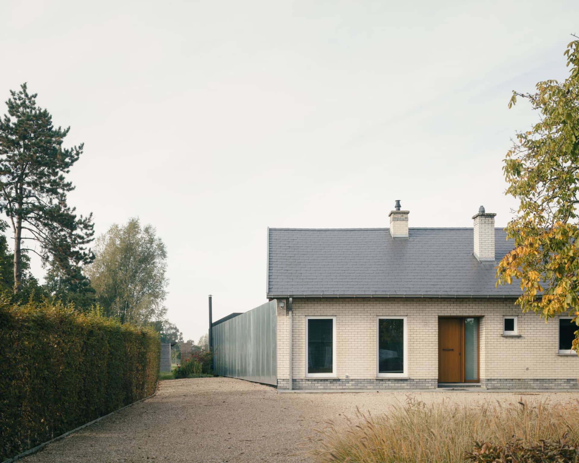 A residential exterior with white brick walls and a metal fence.