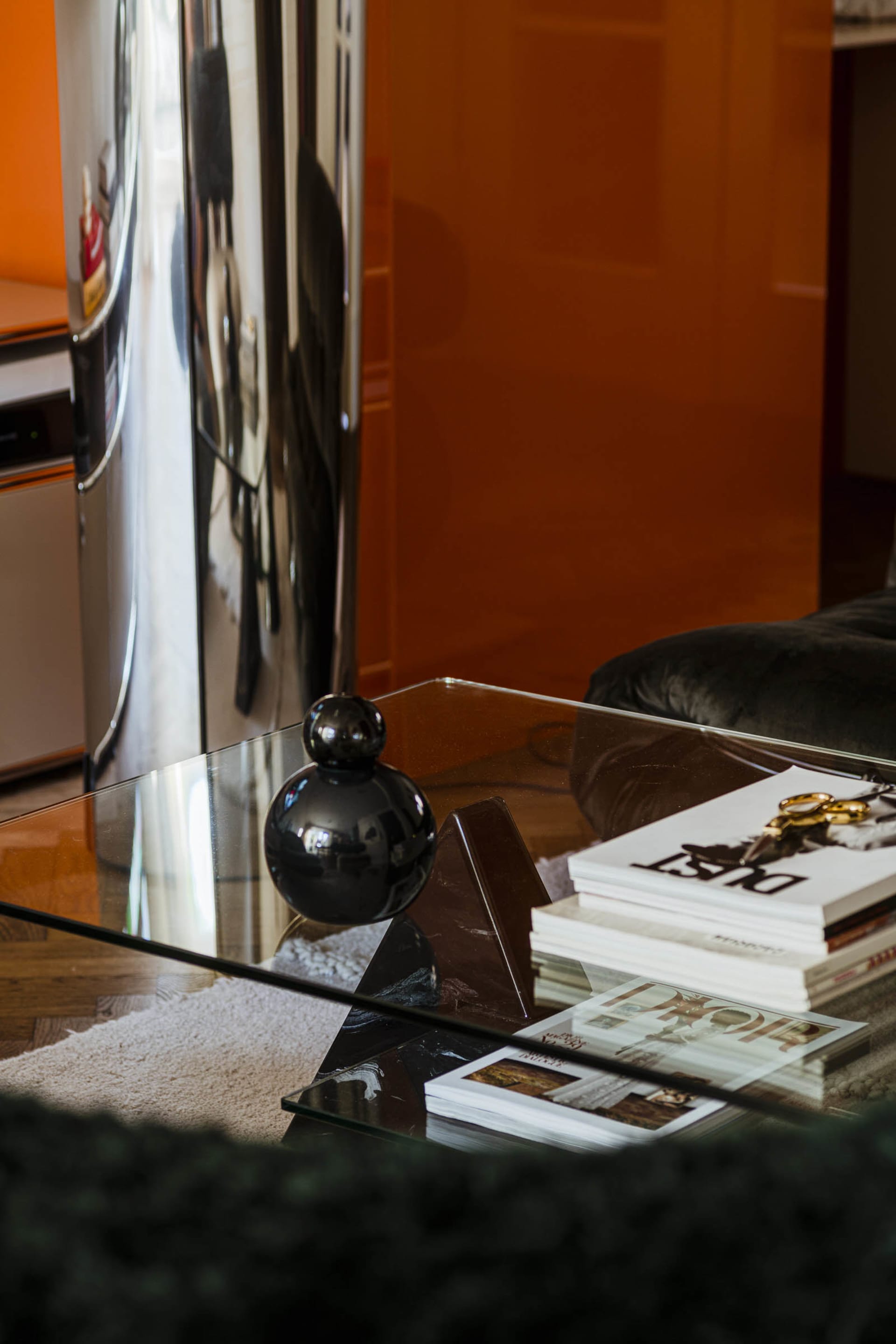 A modern coffee table with glass top and marble base, featuring decorative items and books.