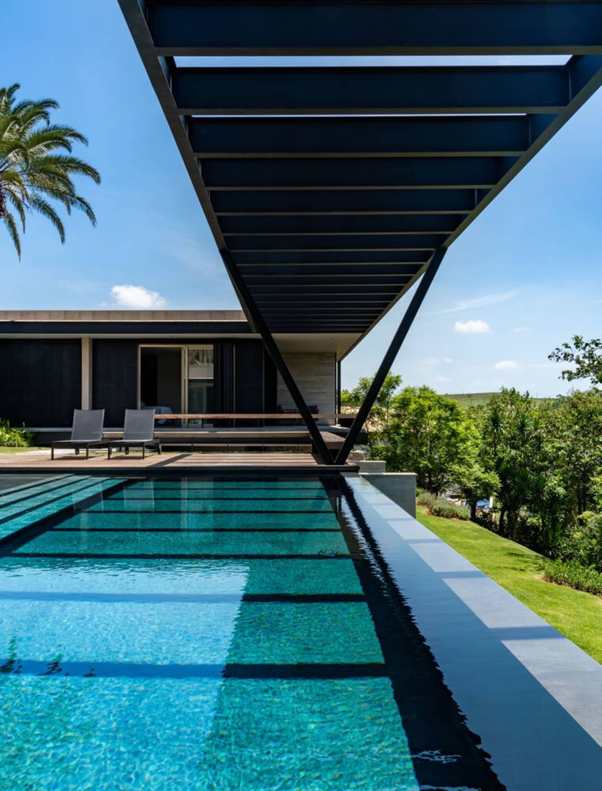 Modern exterior swimming pool with concrete, glass, and steel materials.