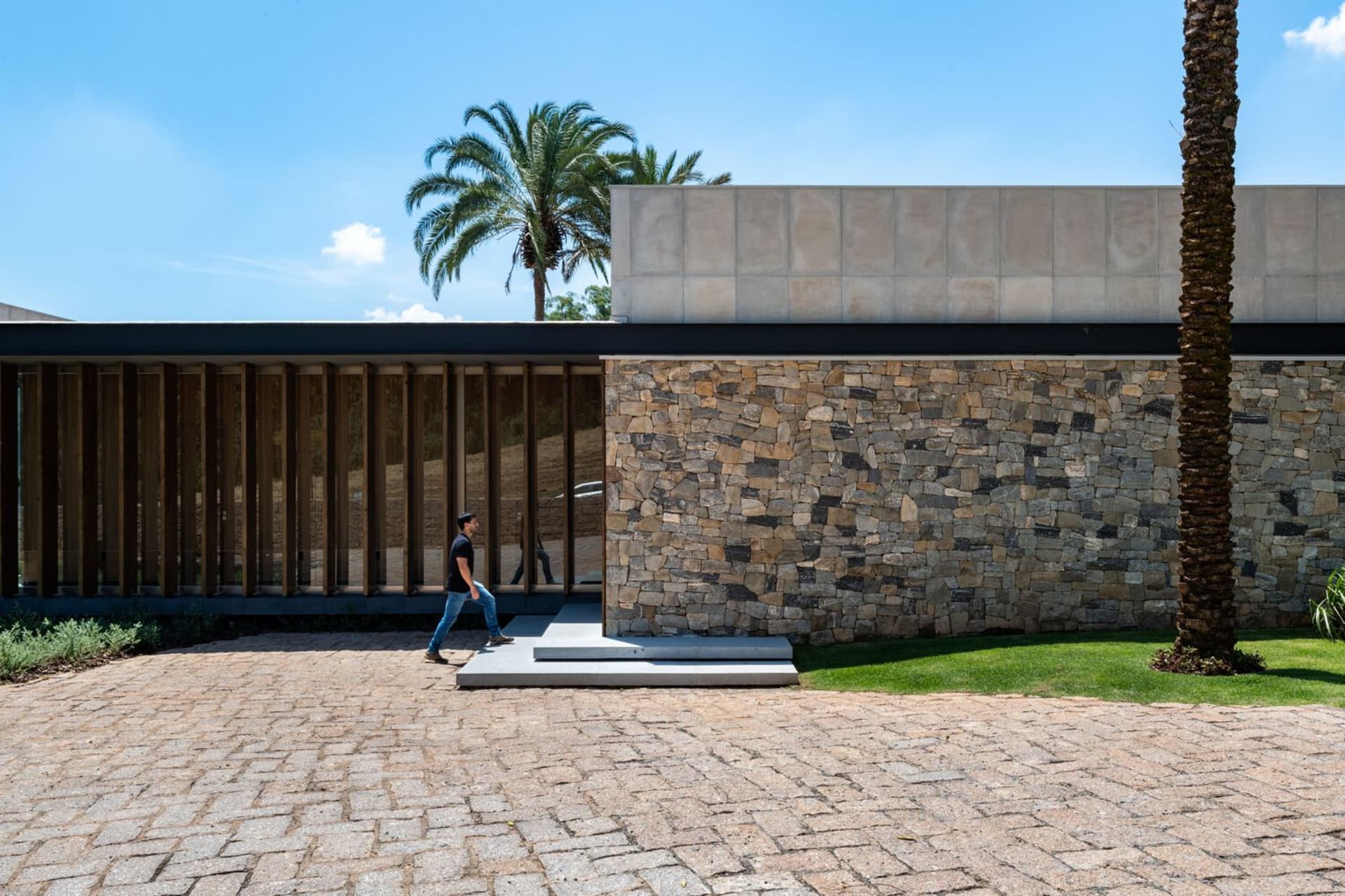 A modern residential exterior featuring stone, glass, and concrete materials.