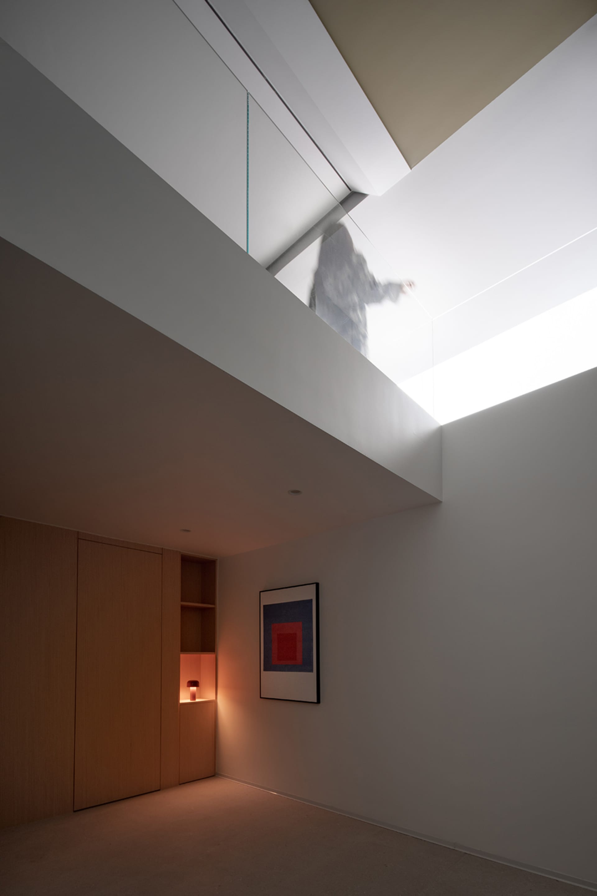 A modern interior space featuring a glass rooflight, minimalistic design, and natural light.