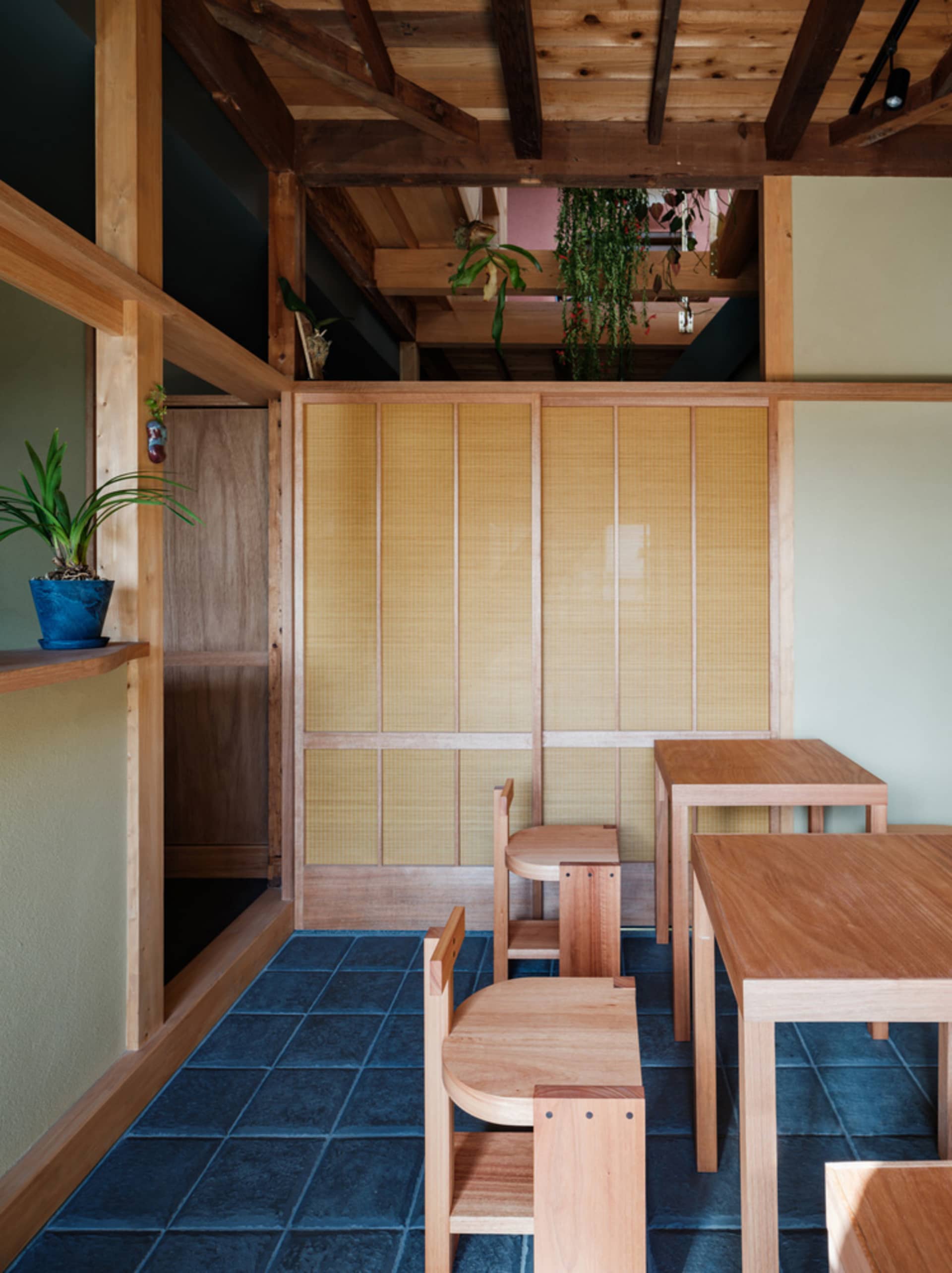 現代餐廳室內擺放木質家具,層架上陳列植物。