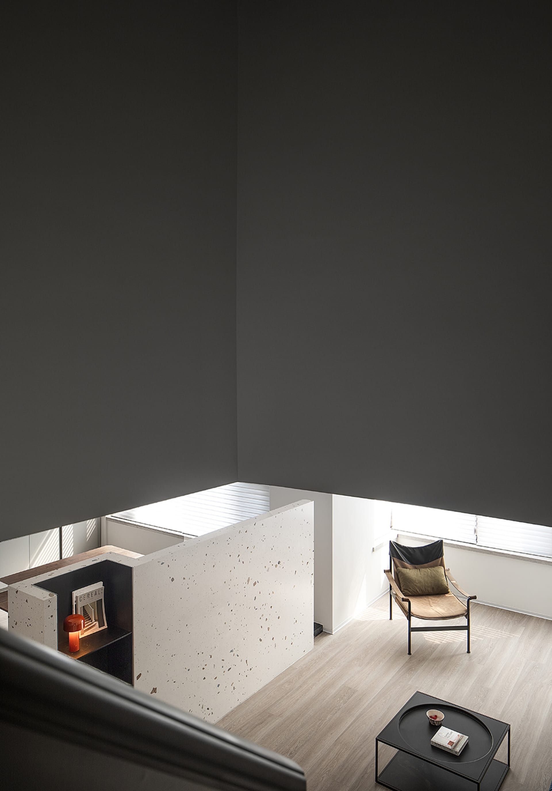 A modern minimalist living space featuring a concrete wall and a single chair.