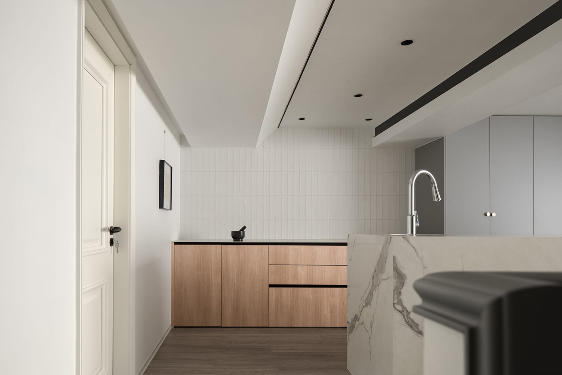 Modern minimalist kitchen with wooden cabinetry and tiled walls.