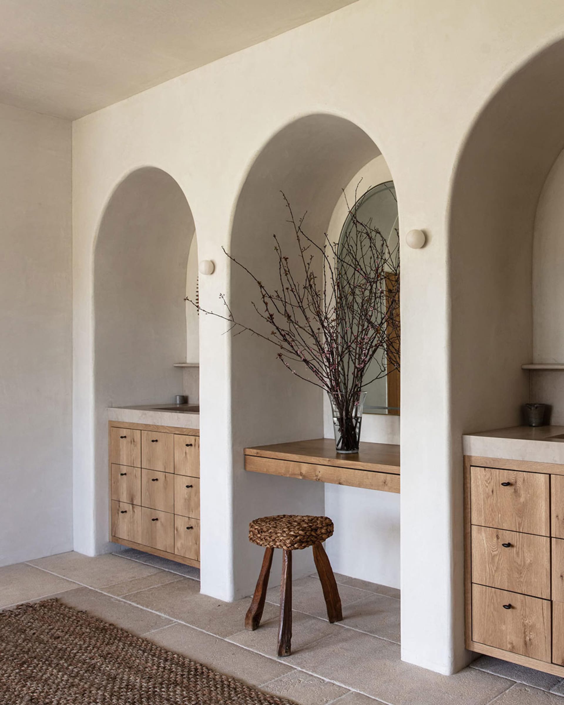 Bathroom interior with modern elements, including concrete cabinets and a wooden countertop with a vase of branches.