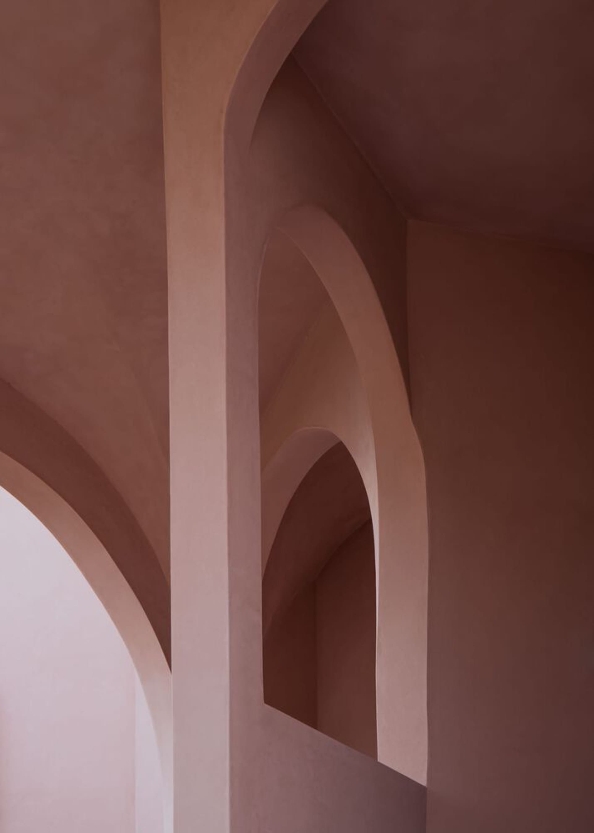 Modern architectural interior featuring concrete walls with integrated arches painted in soft pastel pinks.
