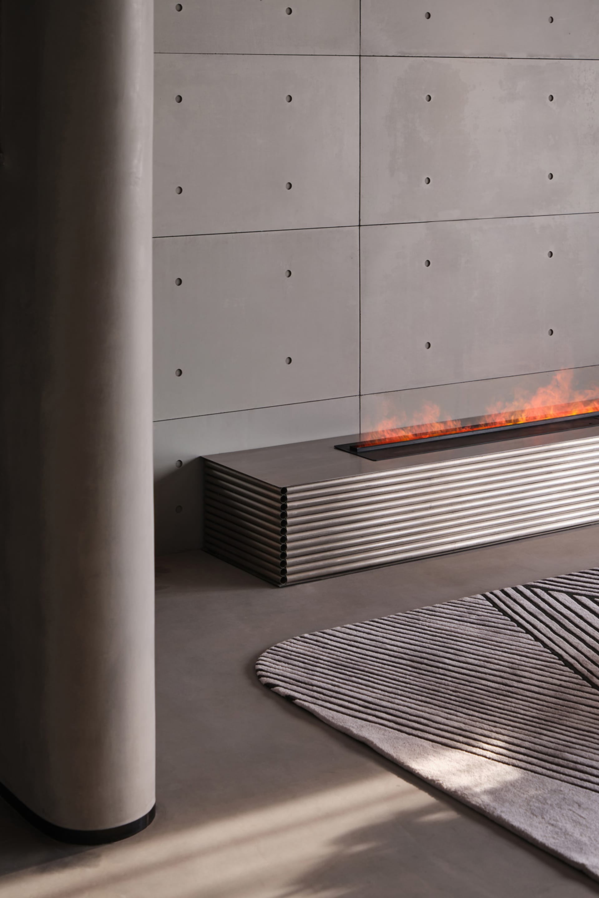 A modern fireplace featuring a concrete wall and steel accents.