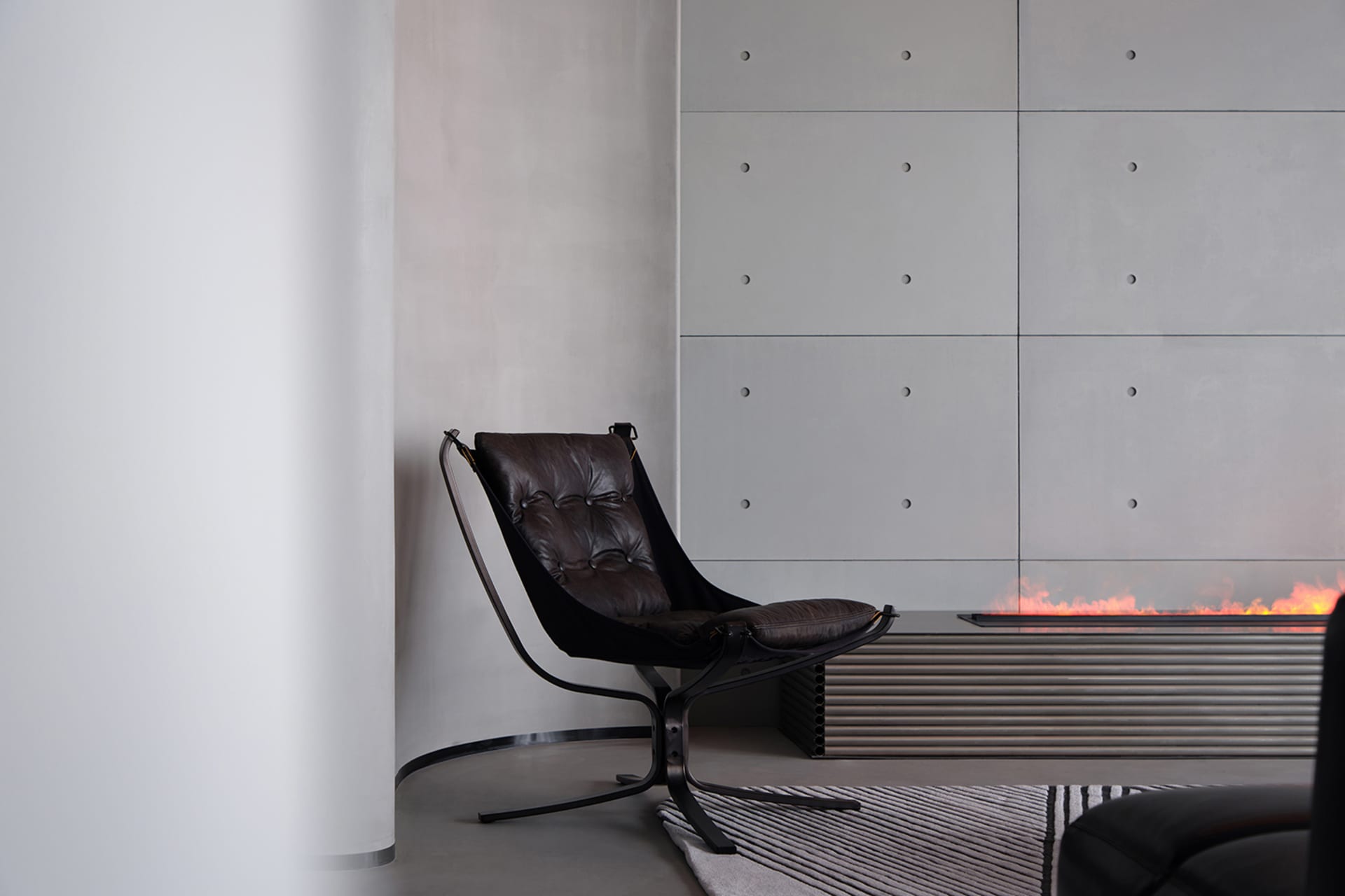 A modern living room with a concrete wall and a black armchair.