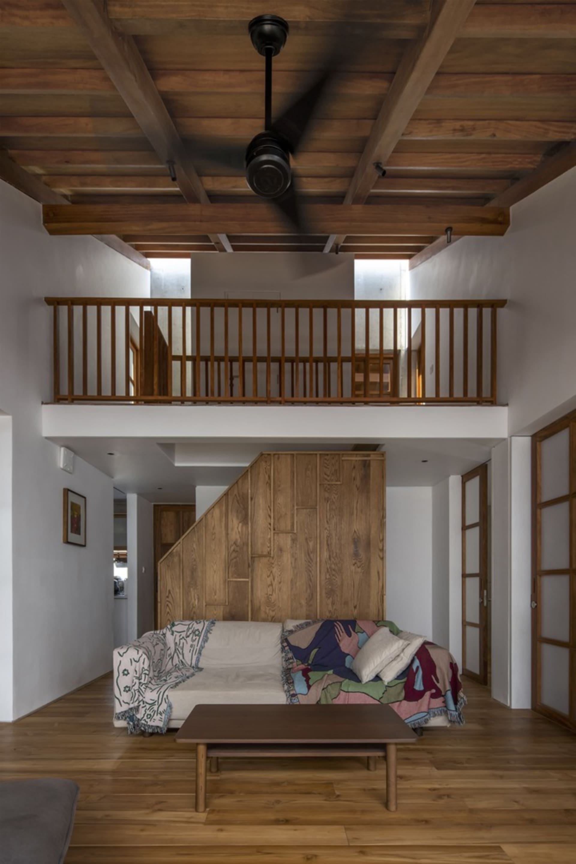 A modern living room with wooden furniture, a coffee table, and a mezzanine area.