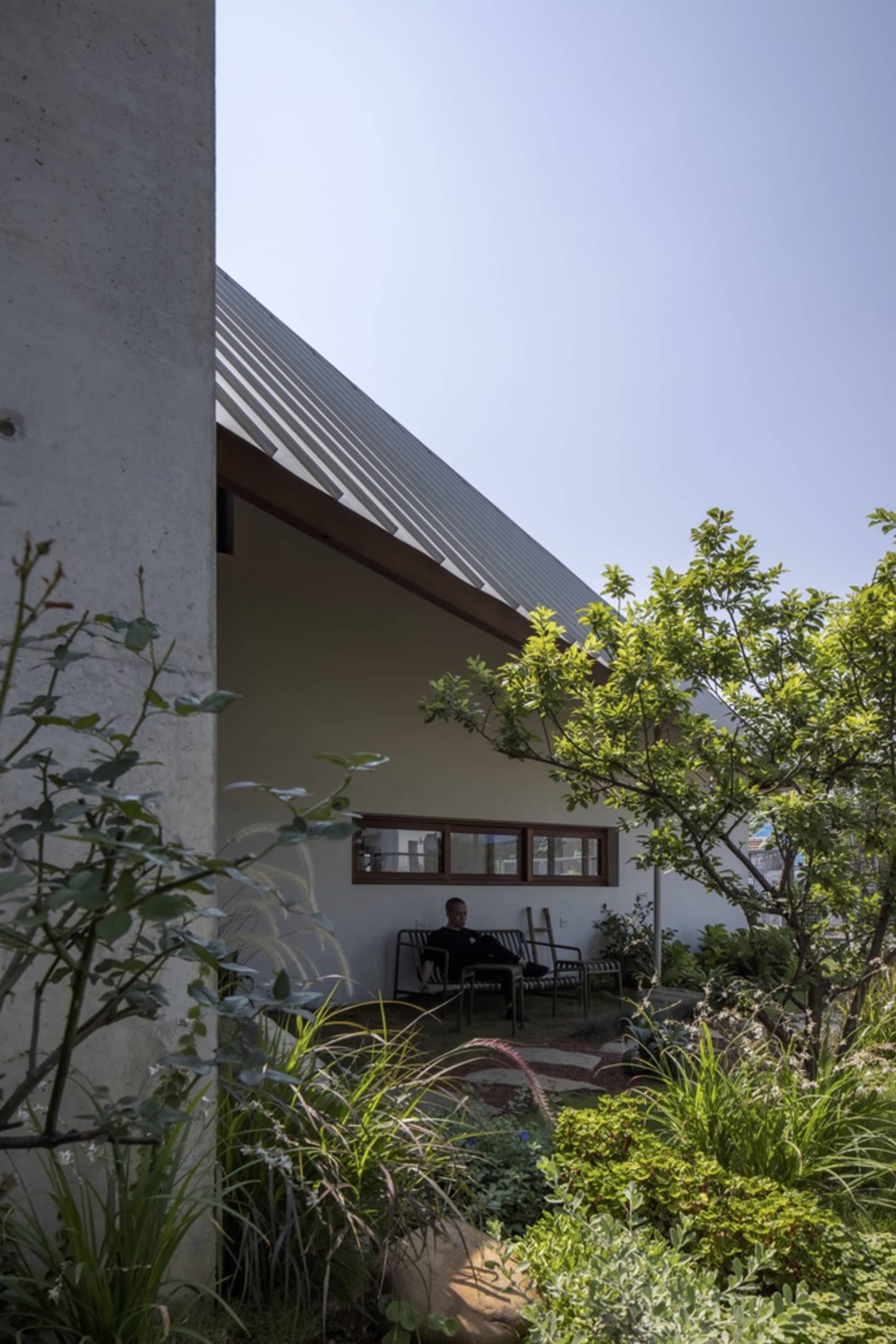 A modern residential exterior with a concrete structure and greenery.