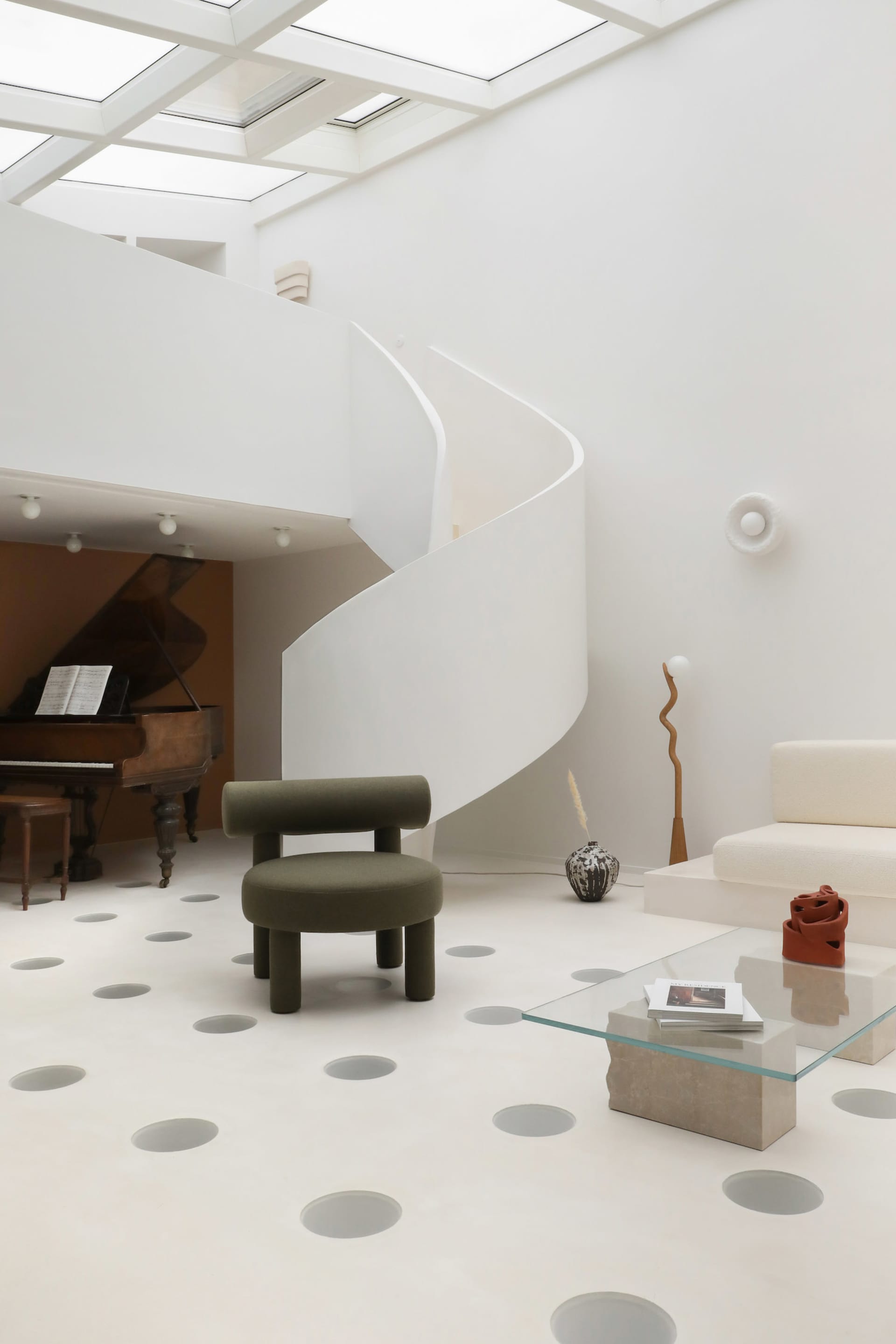 A minimalist interior space featuring a concrete floor with circular patterns and a spiral staircase.