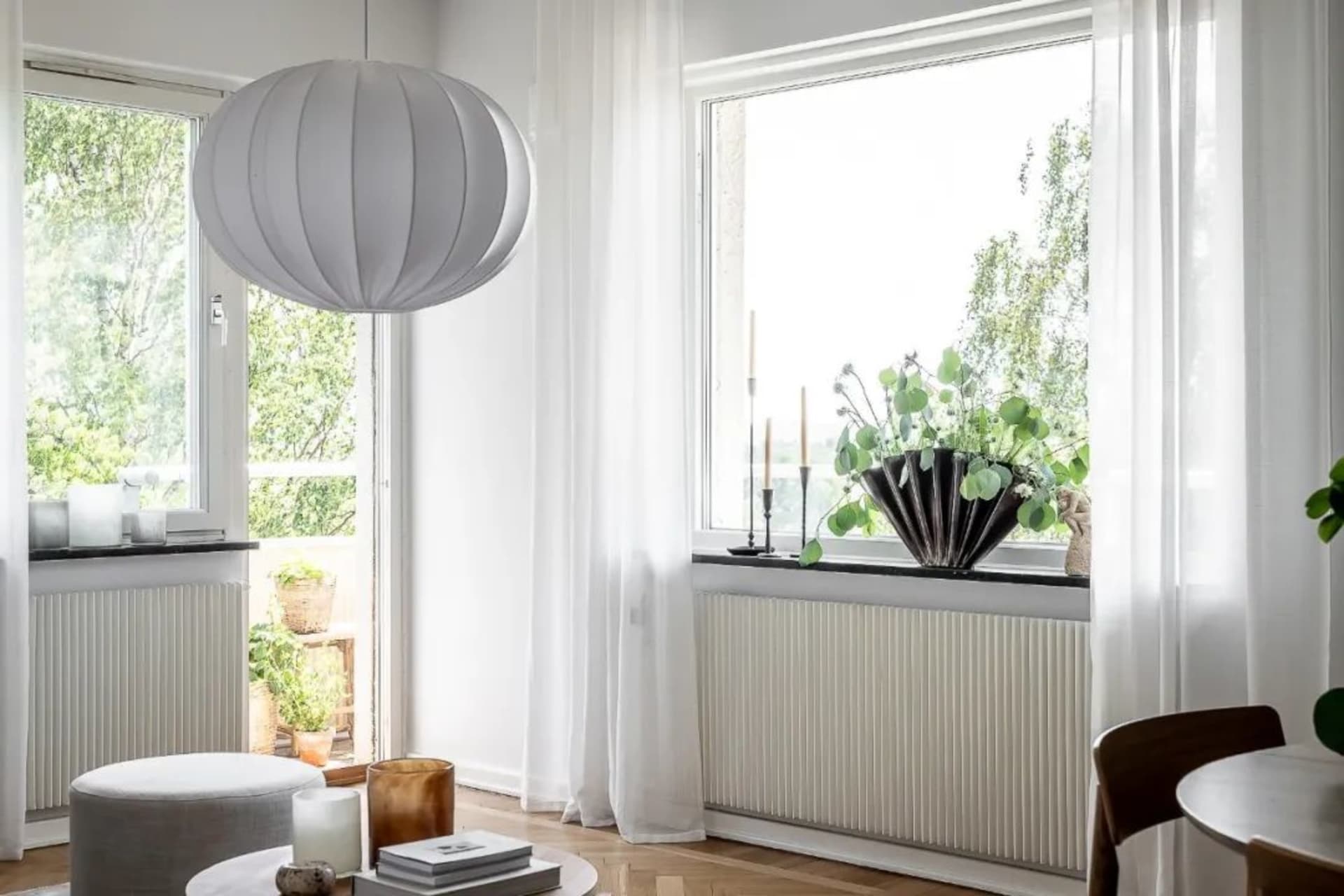 A modern living room with luxurious furniture, white curtains, and a large window.