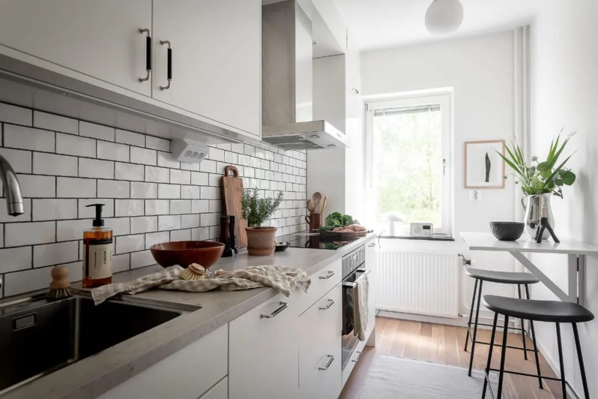Modern, minimalist kitchen with white subway tiles, stainless steel appliances, and wooden accents.