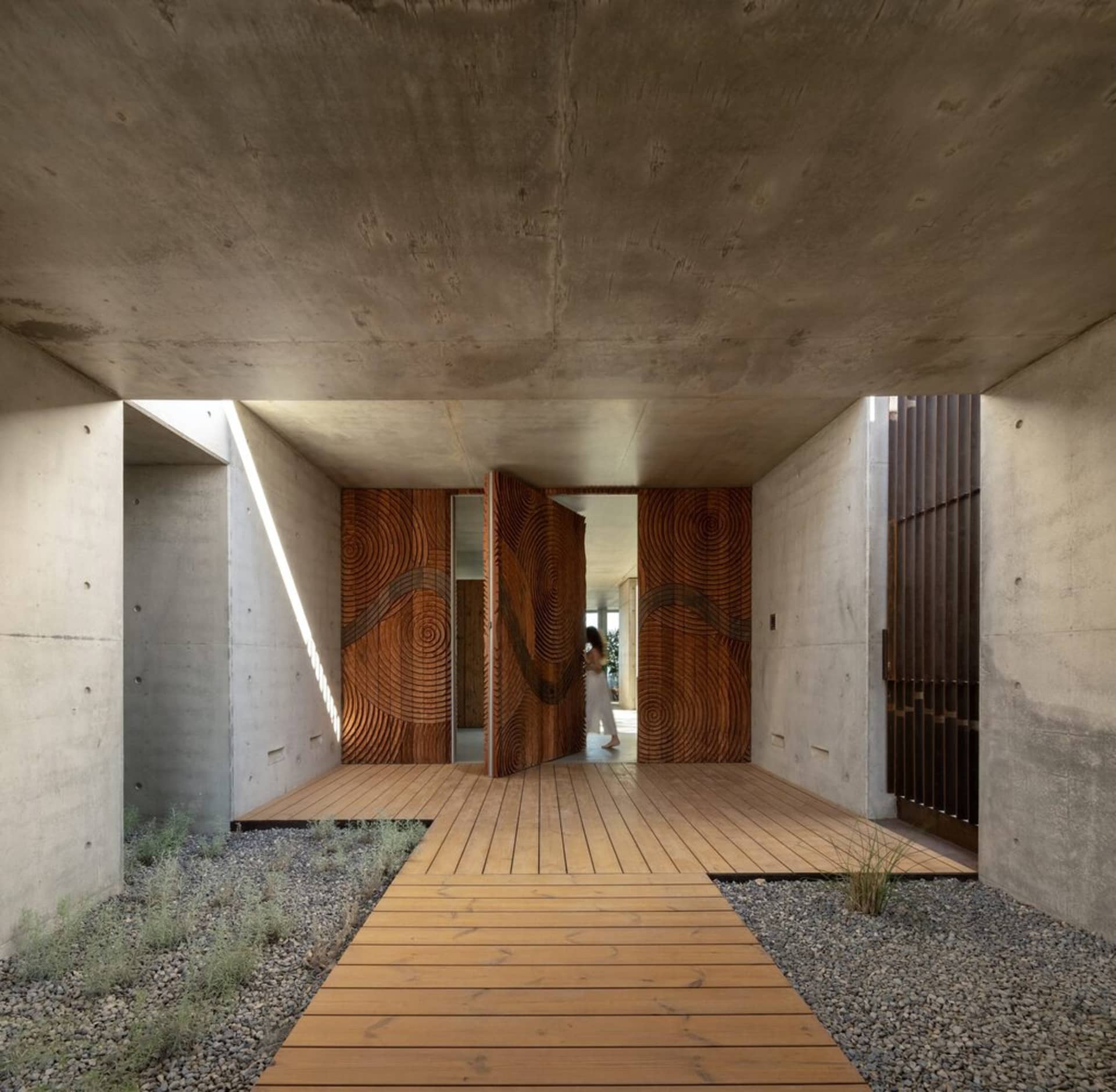 Modern architectural entrance featuring concrete walls and wooden flooring.