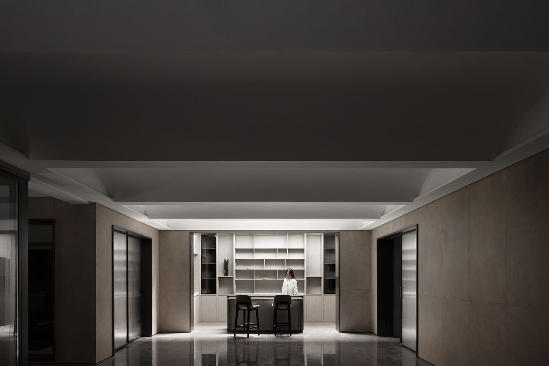 An interior space featuring a modern kitchen with minimalist design, including concrete walls and floor, and a sleek, functio