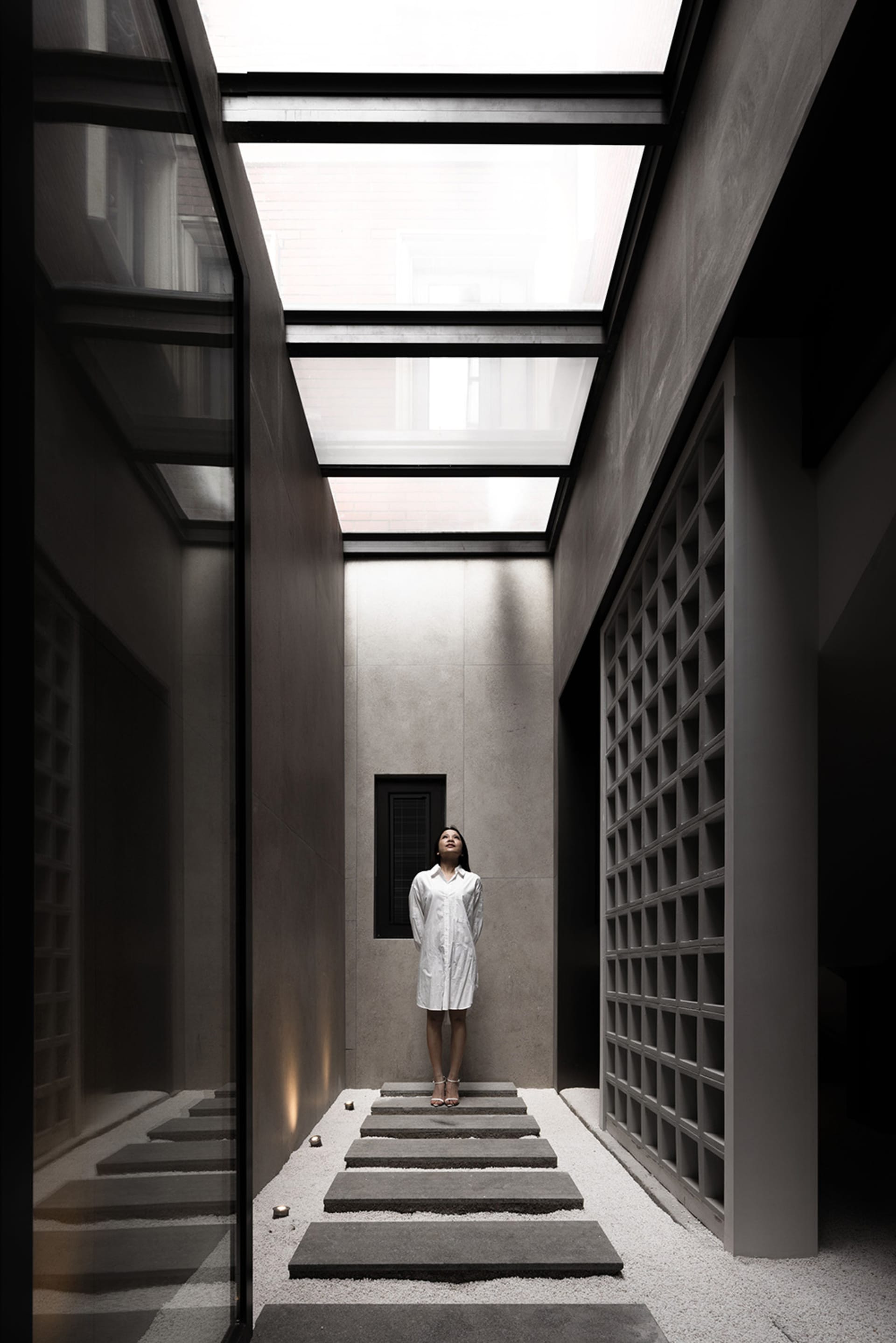 A minimalist interior space made of concrete and glass with a skylight.