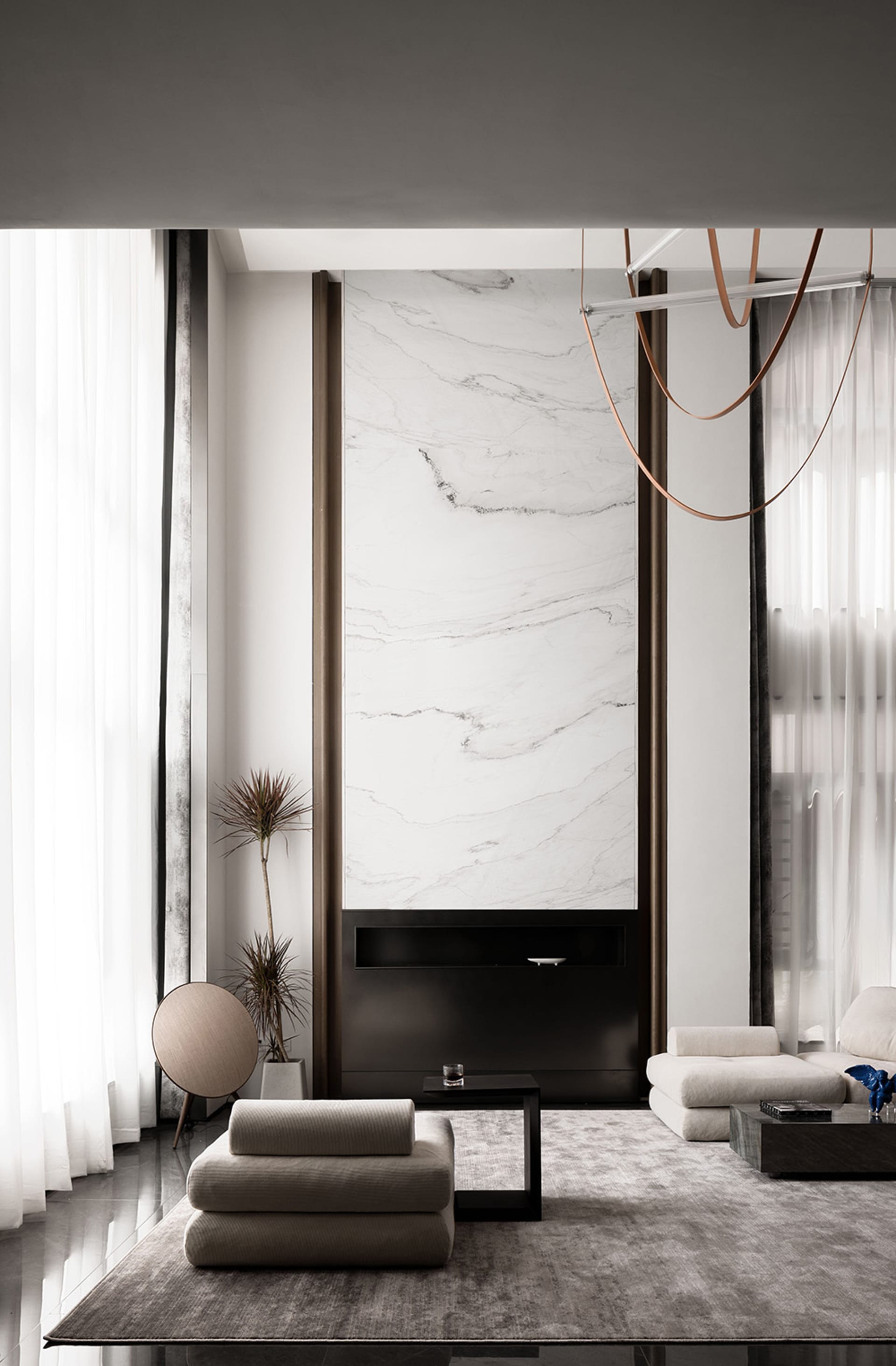 Modern minimalist living room with white marble accent wall, floor-to-ceiling windows, and contemporary furniture.