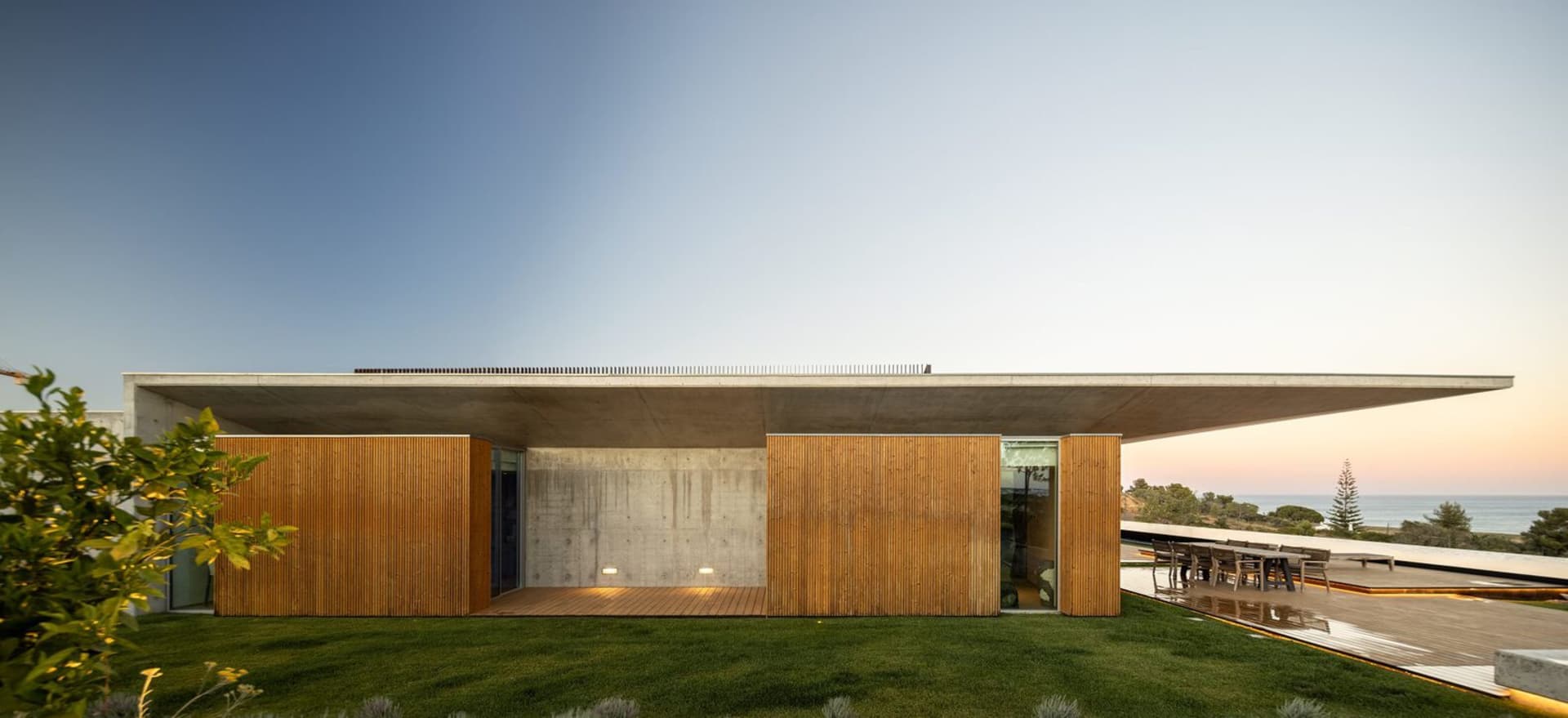 Modern residential exterior with a flat roof, concrete walls, and wooden accents.