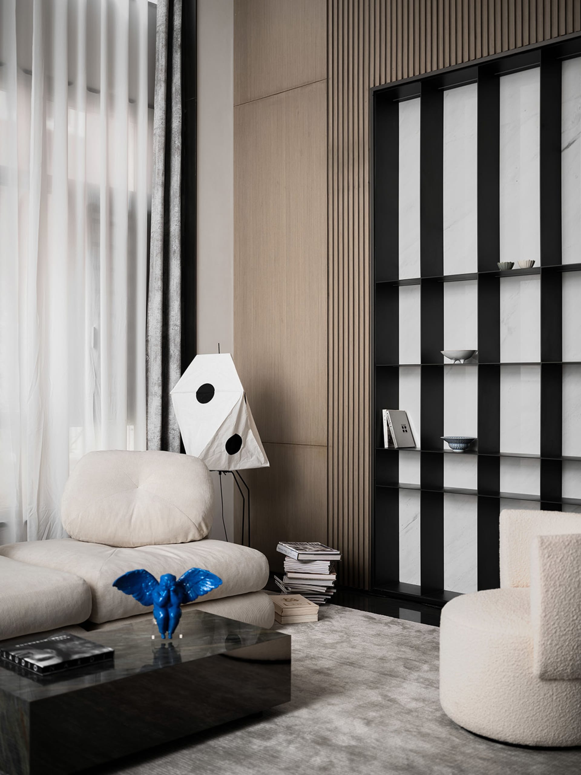 A minimalist living room featuring a textured-wood wall, a comfortable sofa, and a modern coffee table with a blue sculpture.