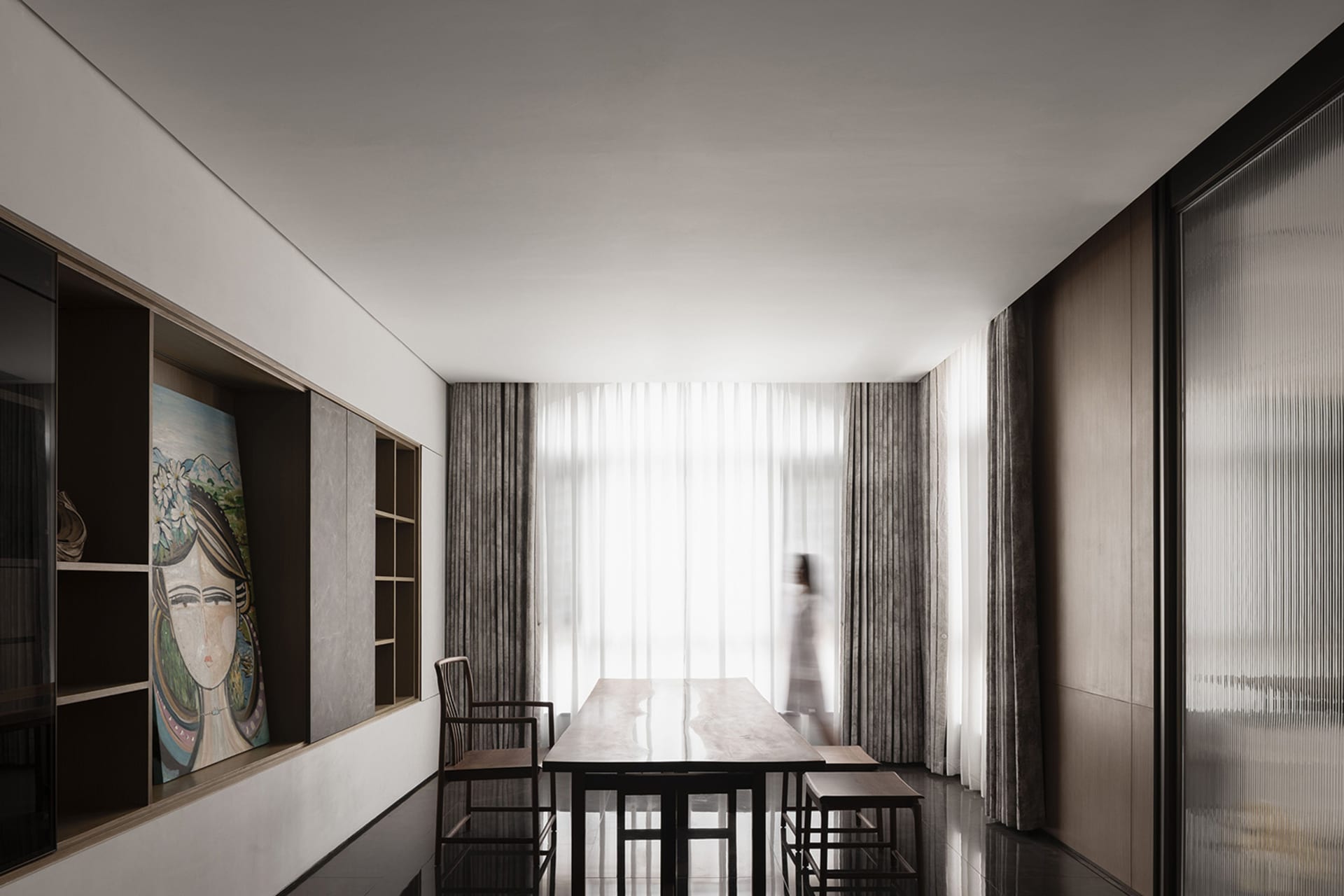 A minimalist dining room with a wooden table, chairs, and curtains.