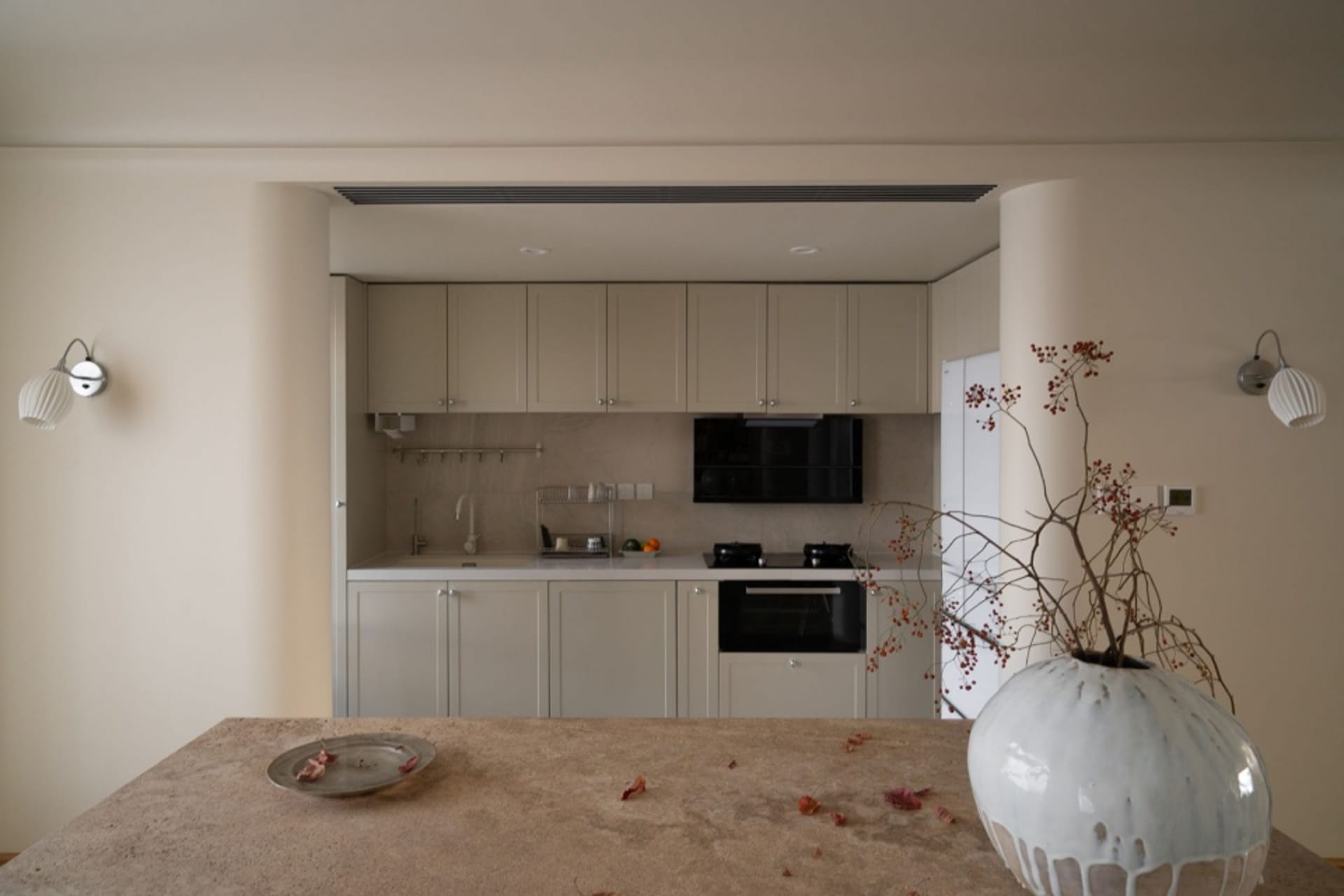 A modern, minimalist kitchen with white cabinetry and marble countertops.