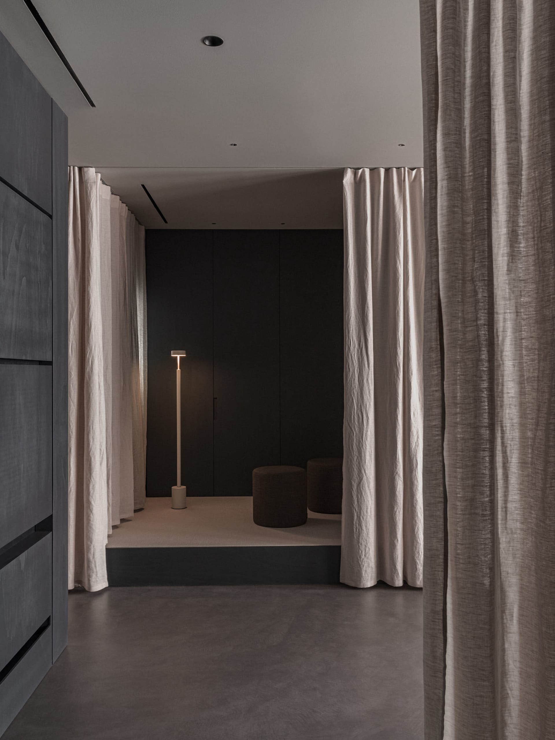 A minimalist living space with neutral-toned textiles and a sleek, modern floor lamp.