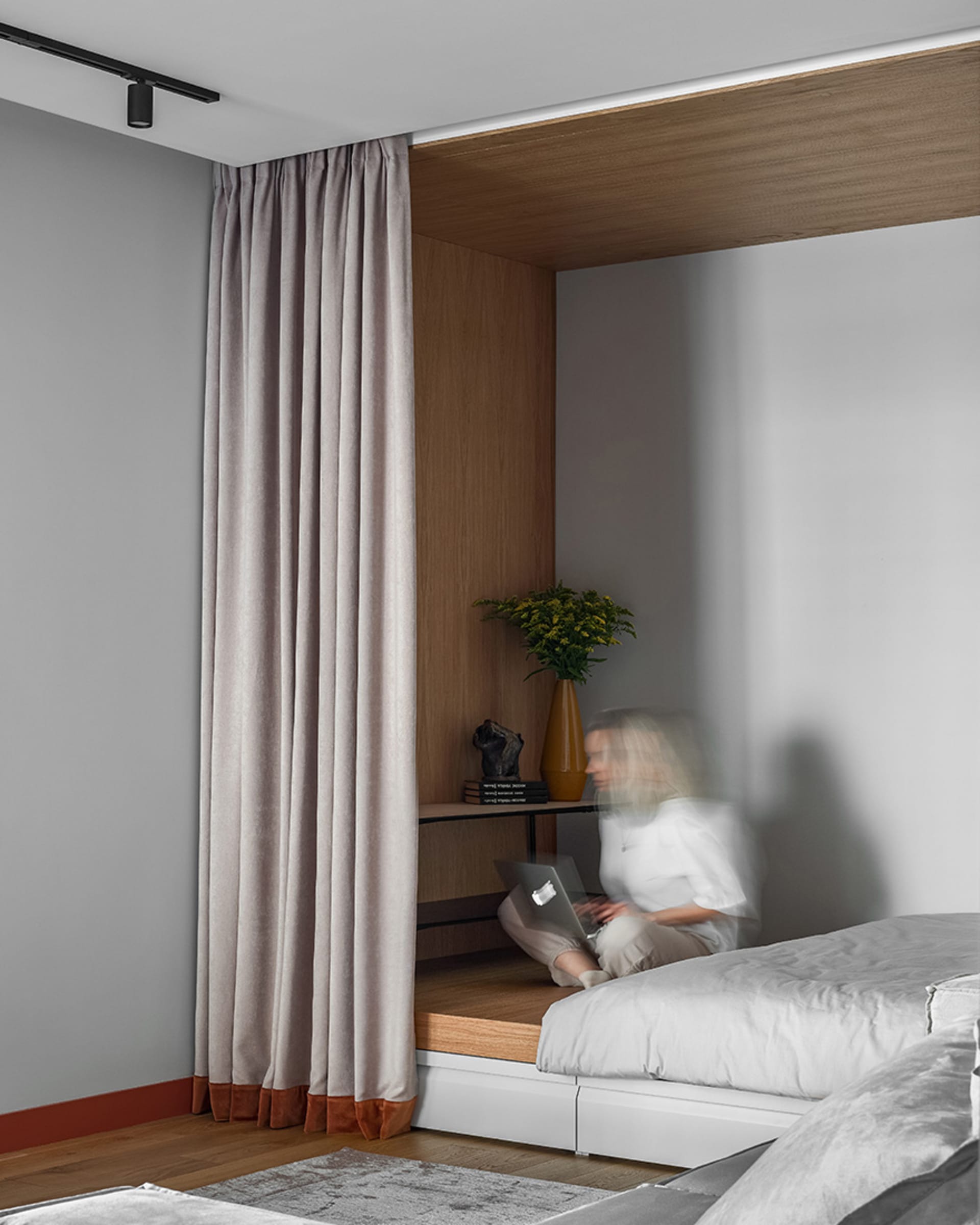 A minimalist bedroom with wooden furniture and a large window covered by curtains.