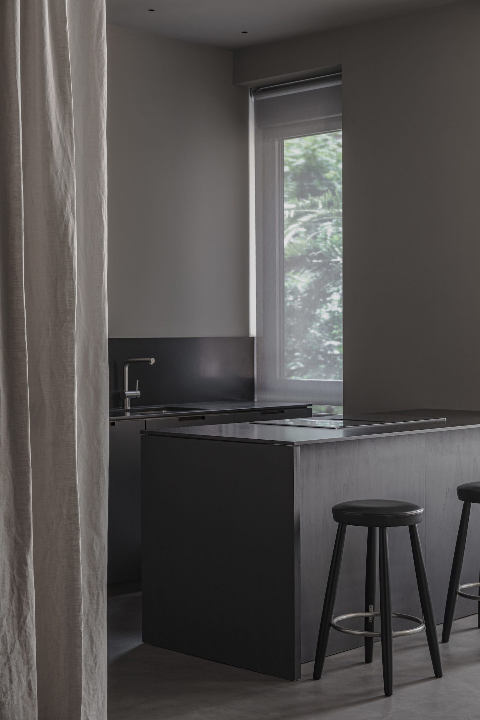 Modern minimalist kitchen with black cabinets, stainless steel appliances, and a black countertop.