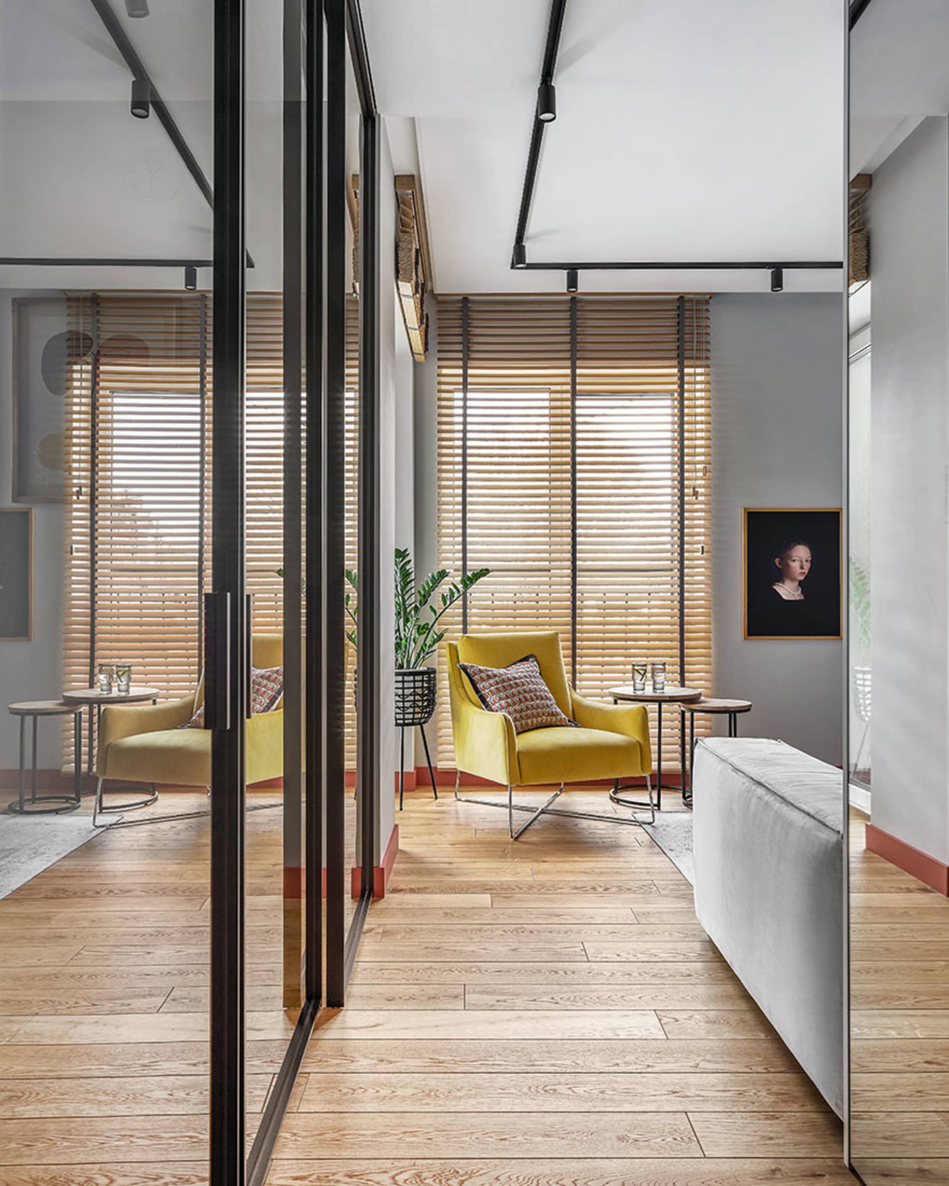 A modern living room featuring a yellow upholstered chair with a cushion, placed on a wooden floor and complemented by wooden