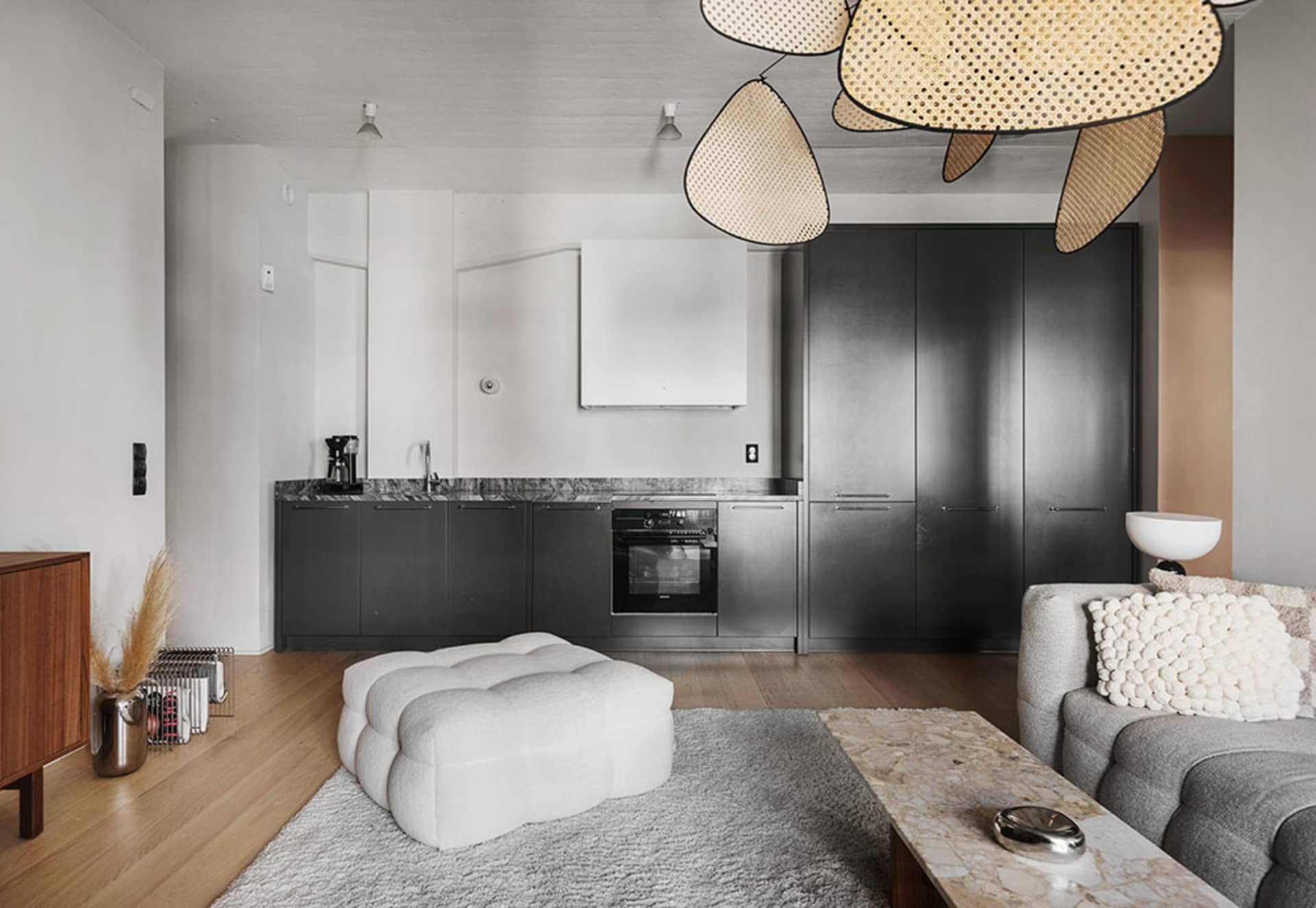 Modern living room with marble flooring and wooden accents, featuring a comfortable seating area and a sleek kitchen in the b