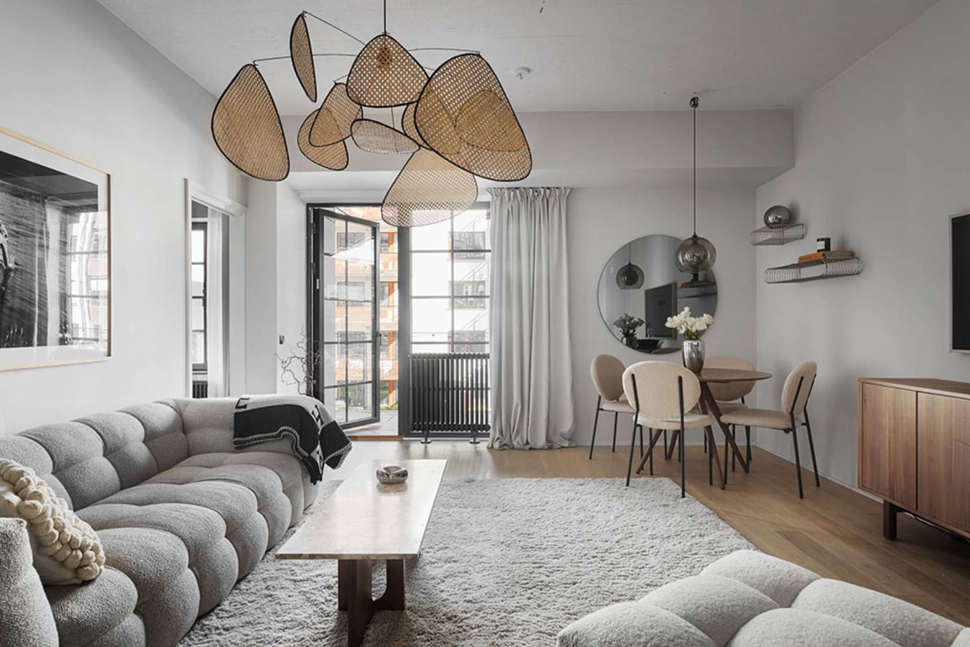 Modern living room featuring plush upholstered furniture, a cozy white rug, unique rattan pendant lights, and a comfortable r