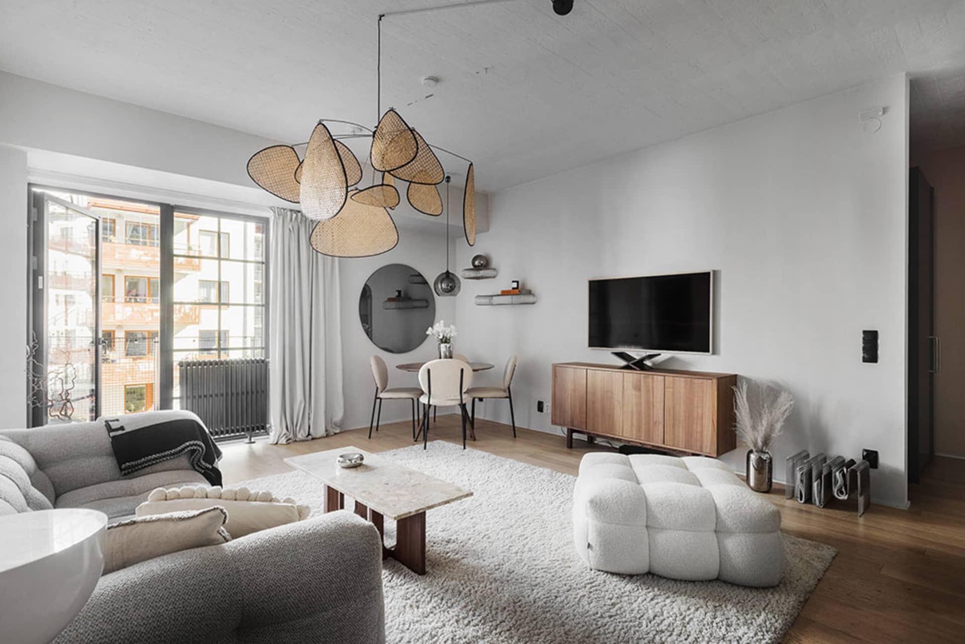 A minimalist living room featuring a grey sofa, marble coffee table, and concrete floors.