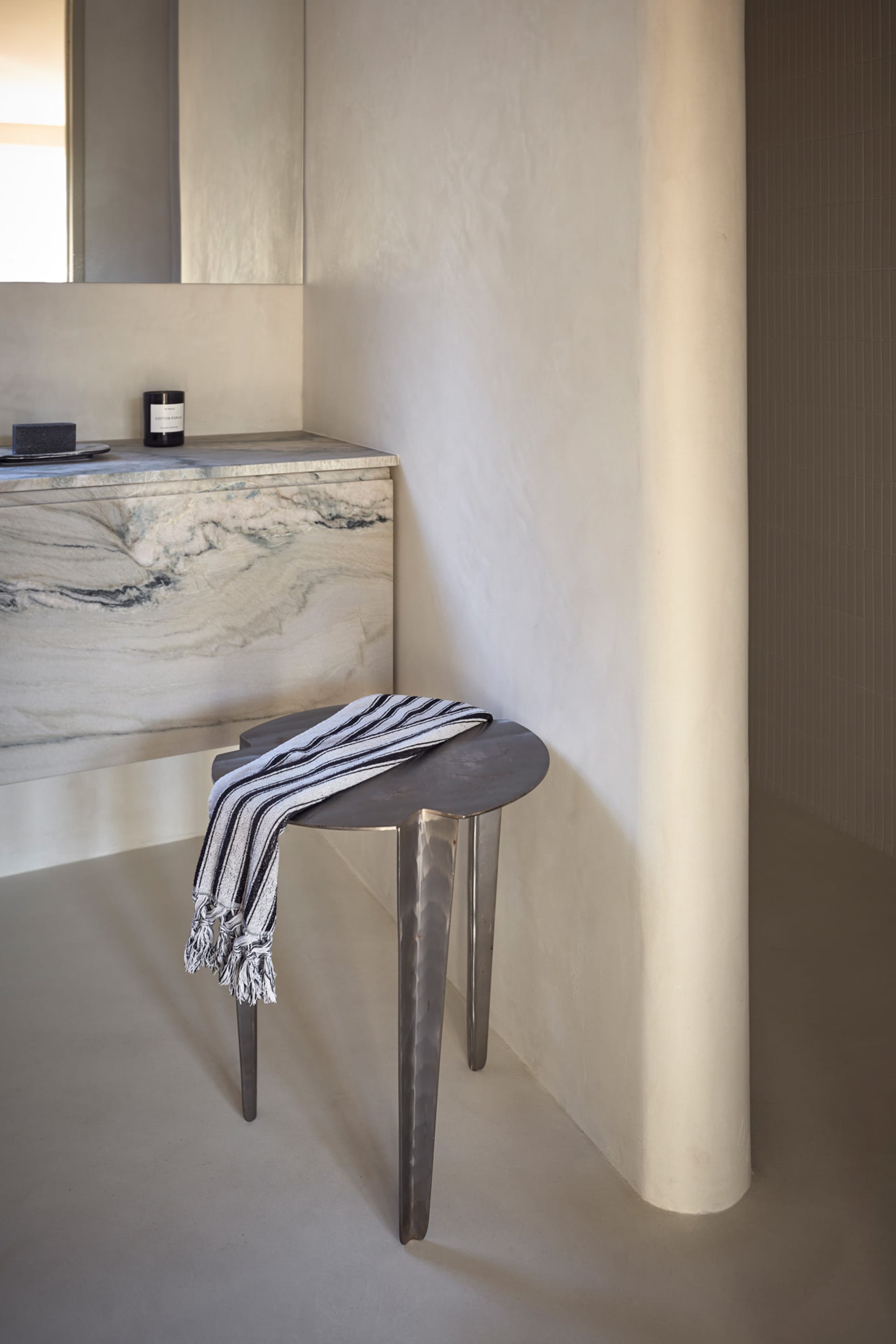A minimalist bathroom with a marble countertop and stool.