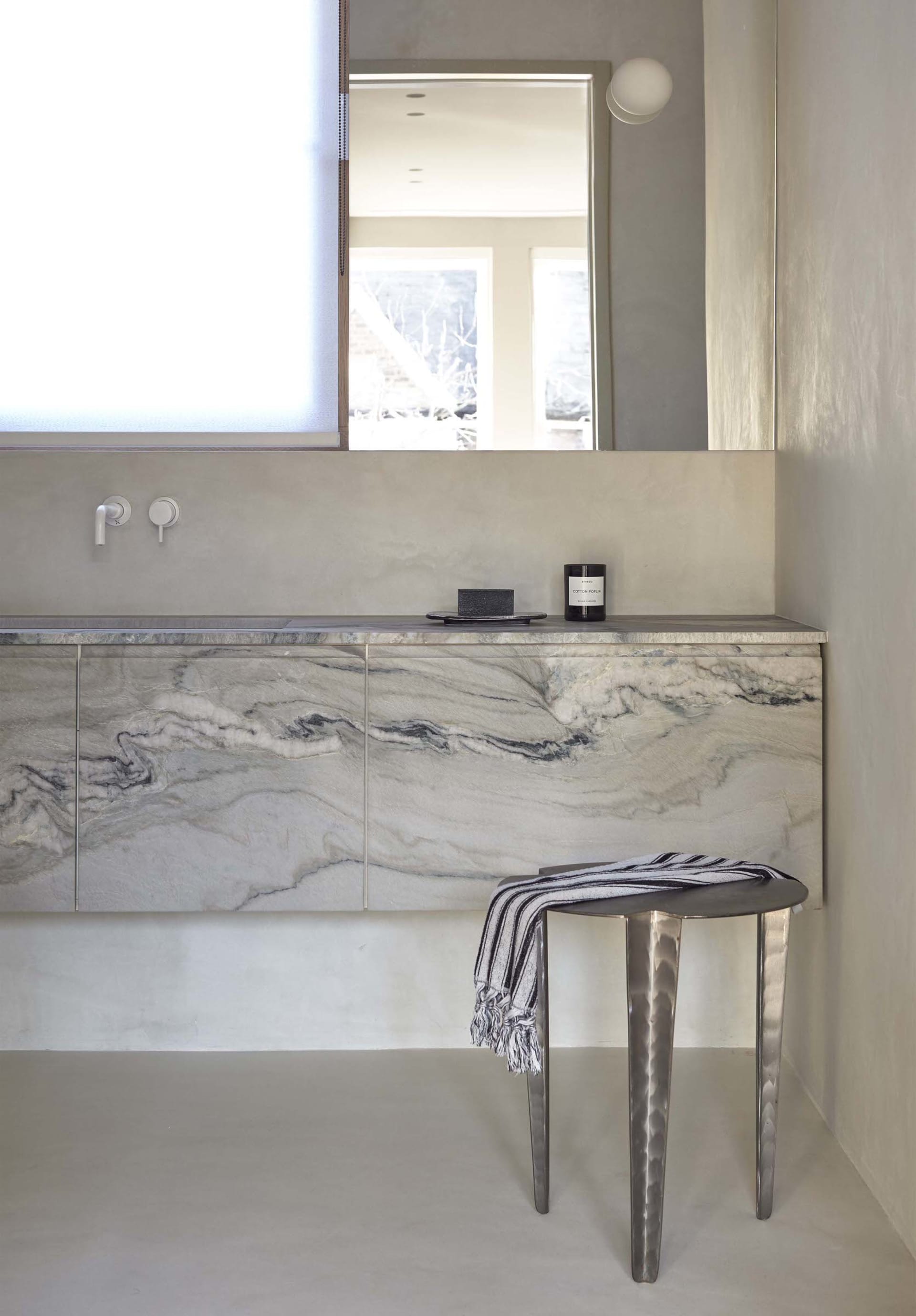 A modern bathroom featuring marble and concrete elements.