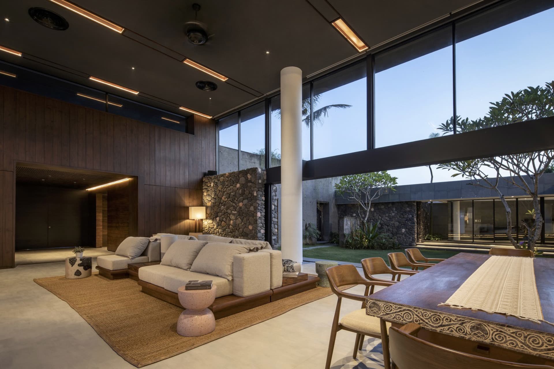 Modern living room with concrete walls and large windows overlooking greenery.