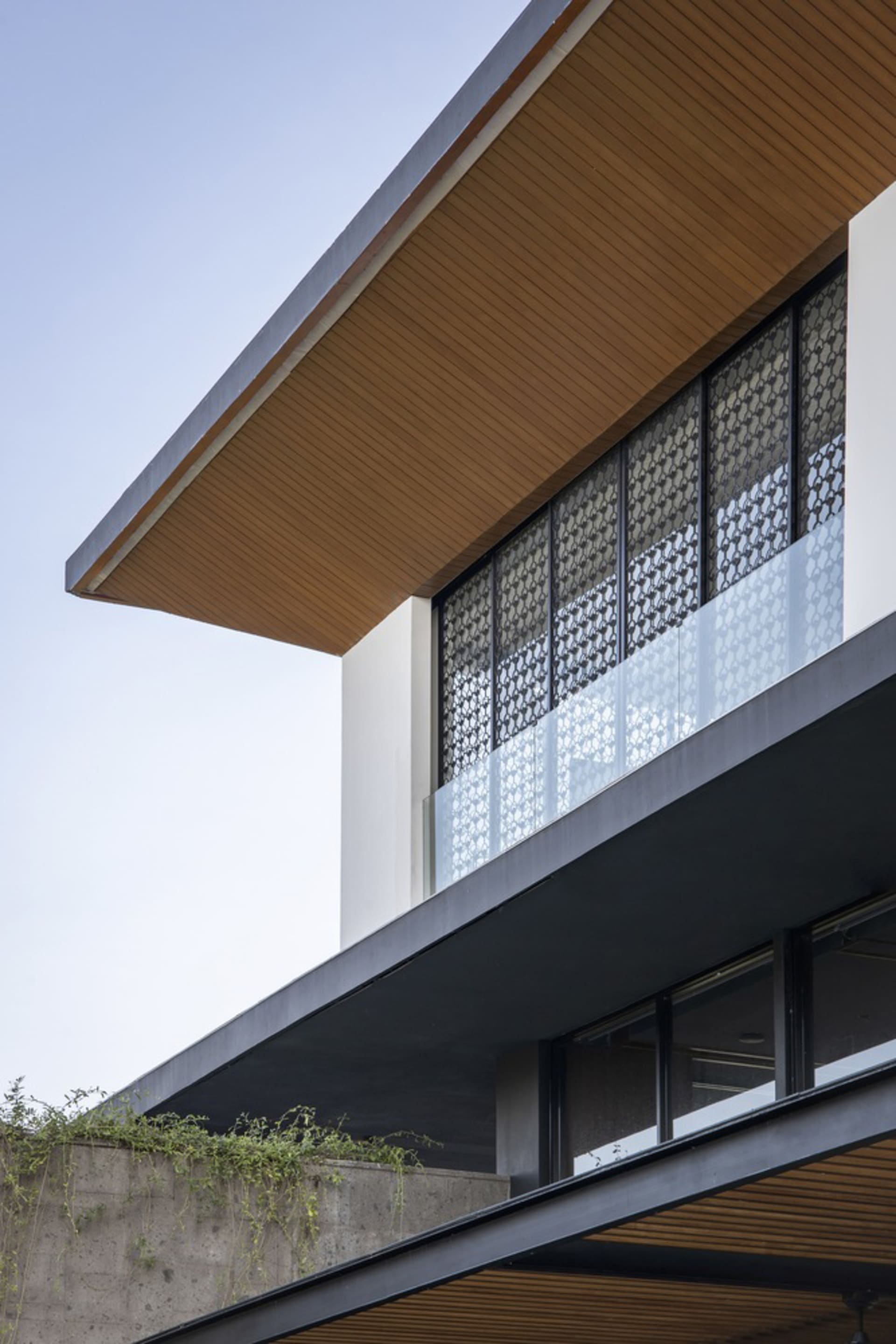 A modern residential balcony with wood-paneled roof and glass balustrade.
