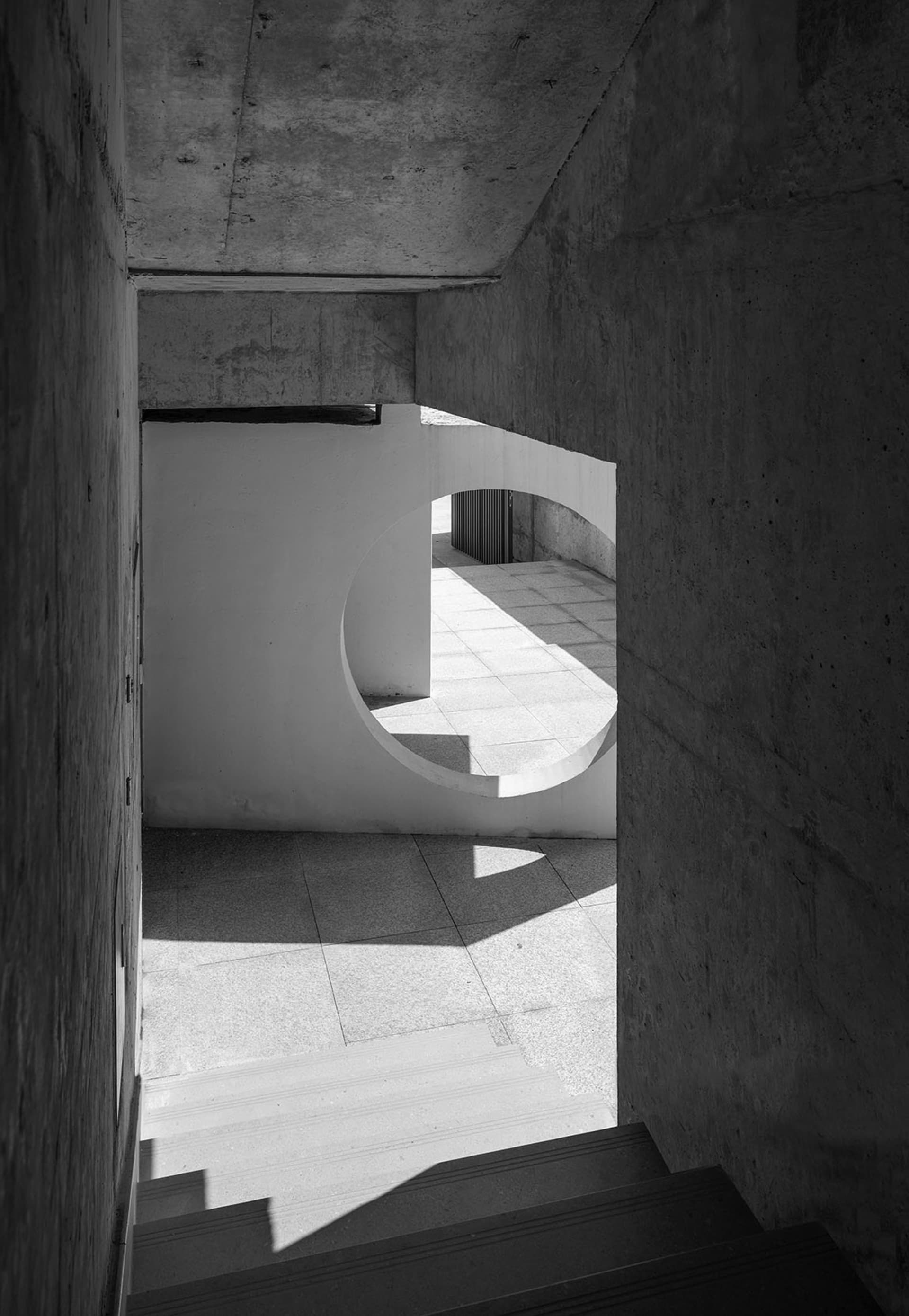 A modern architectural space featuring a concrete interior with lighting and circular archways.