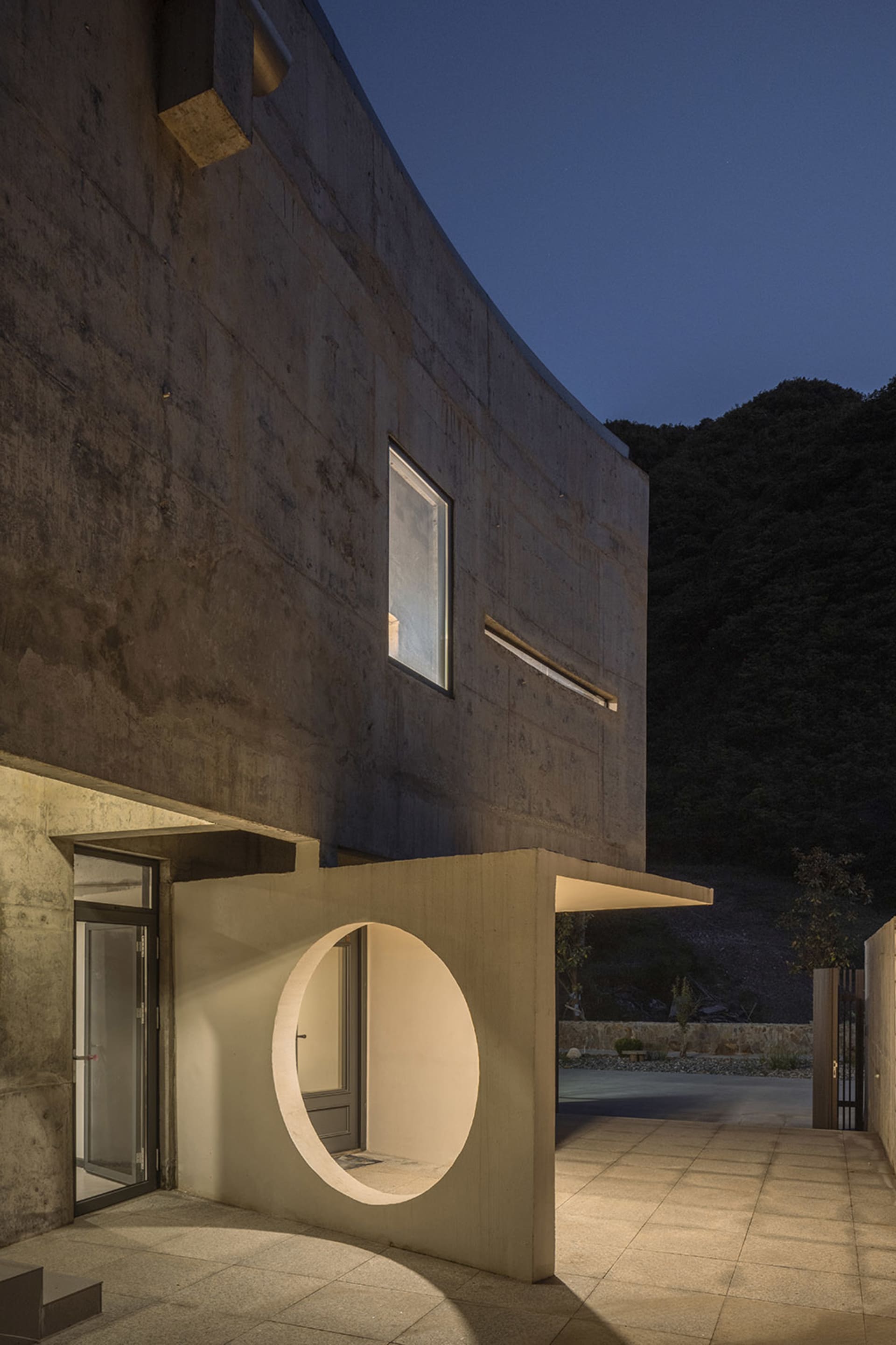 Concrete building exterior with circular entrance at night.