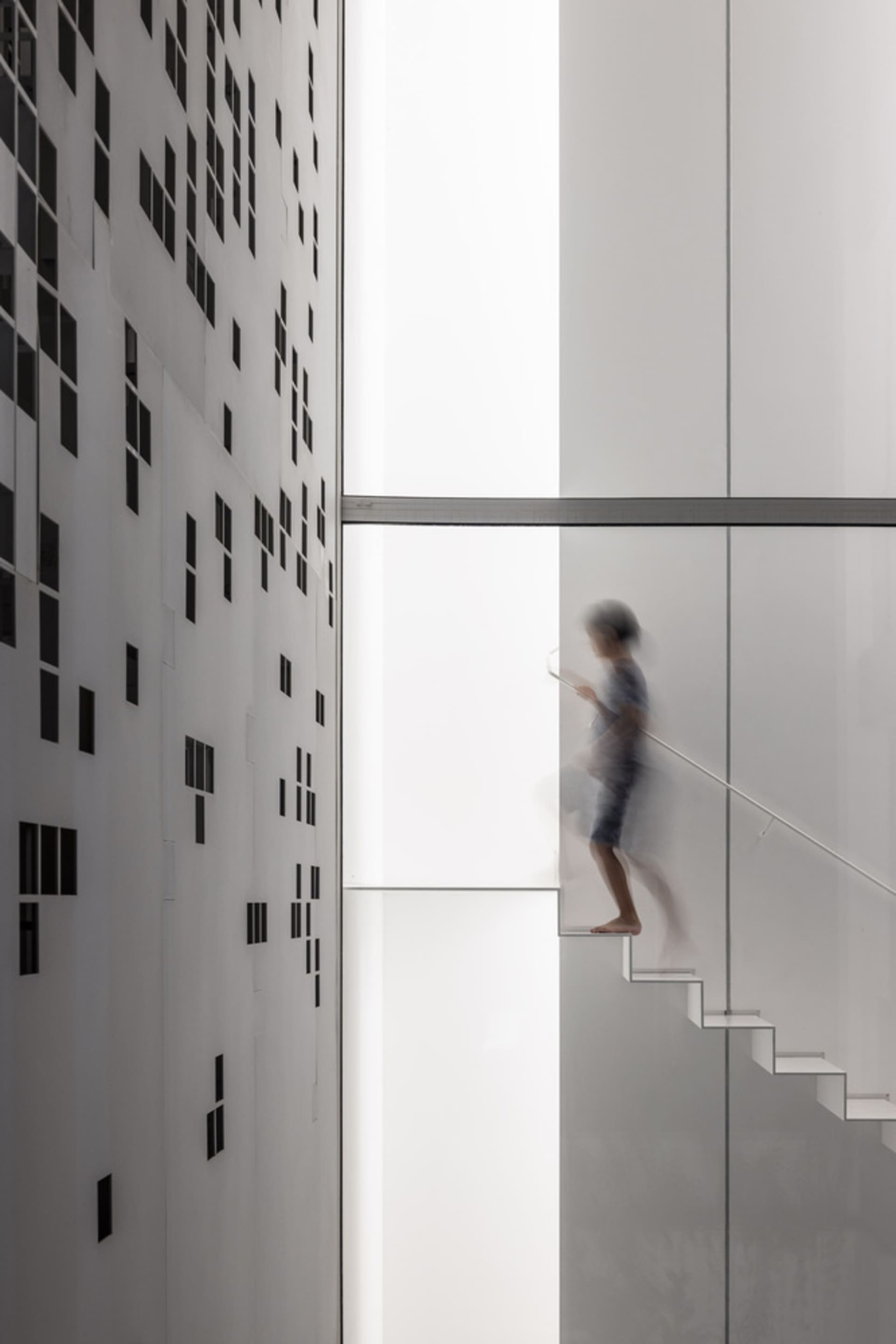 A blurred figure walking on a glass stairway with a modern architectural design.