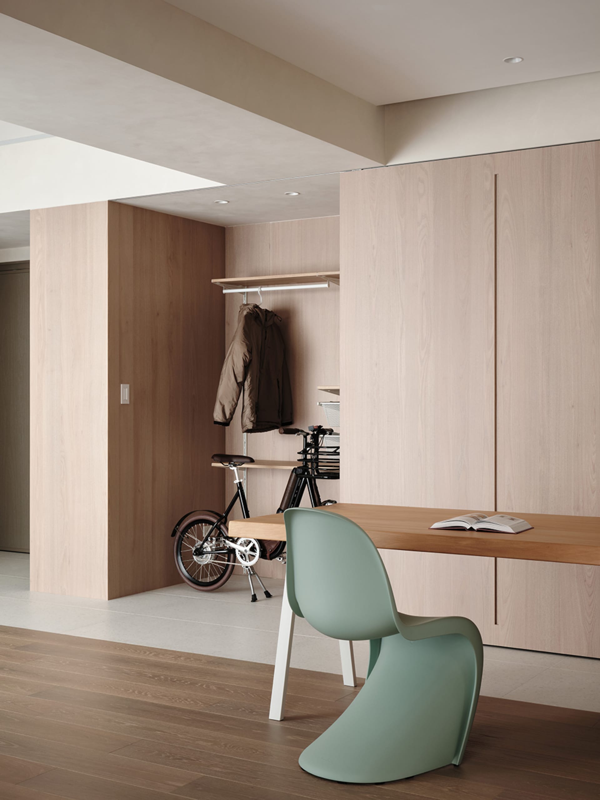 A modern home office featuring a wooden desk, a green chair, and a white wall.