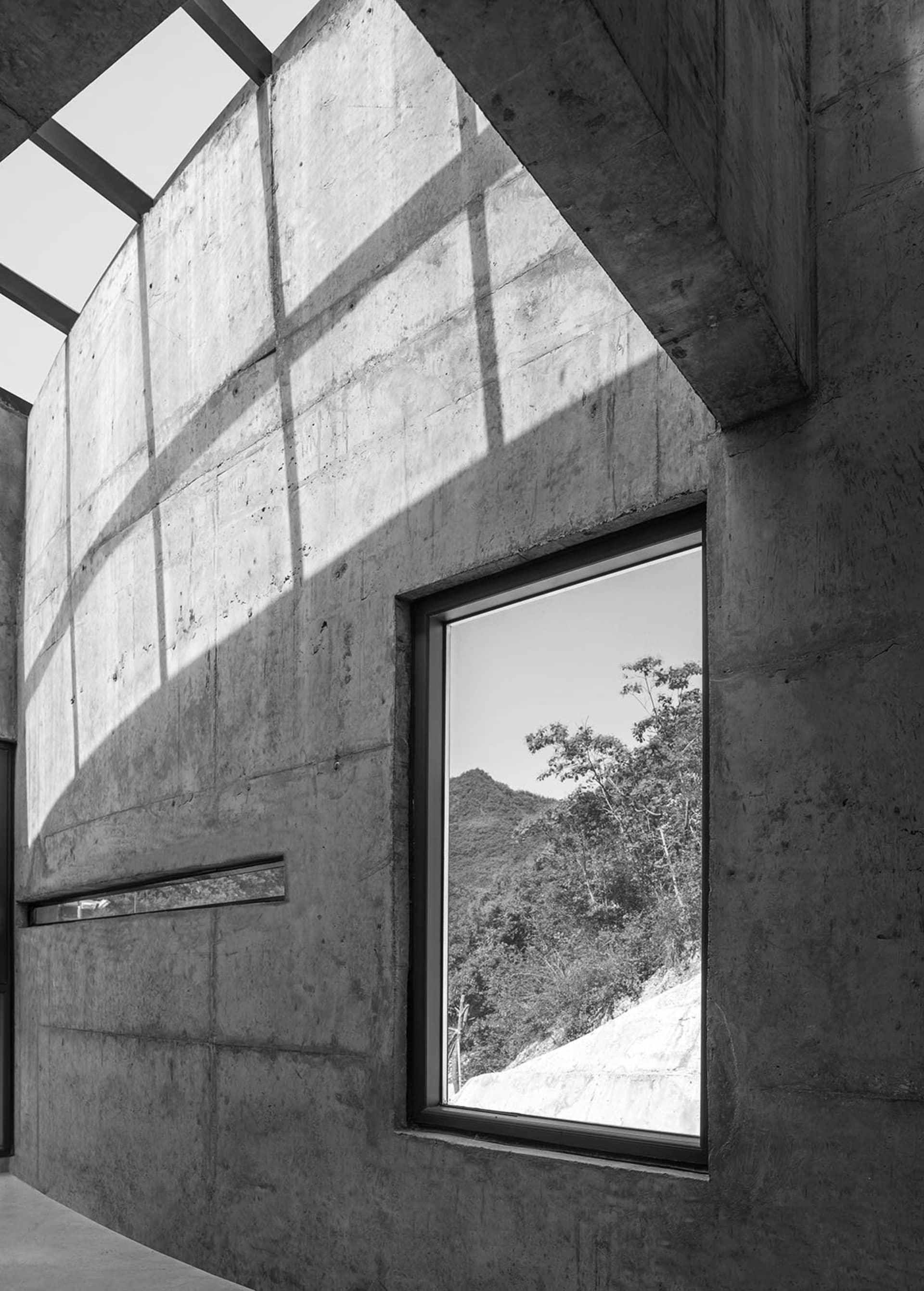 A modern interior space featuring concrete walls with a window showcasing a natural landscape.