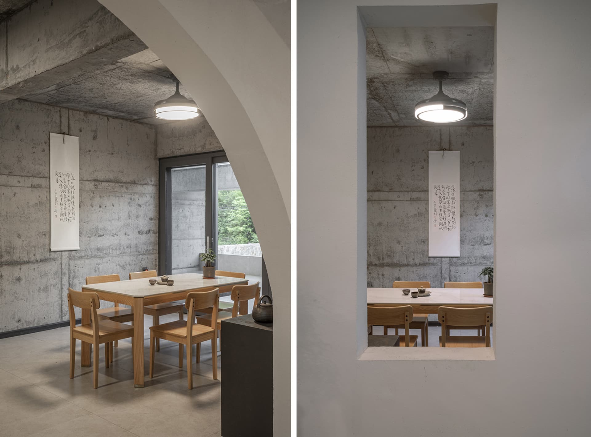 A modern minimalist dining room with concrete walls, wooden furniture, and a ceiling fan.