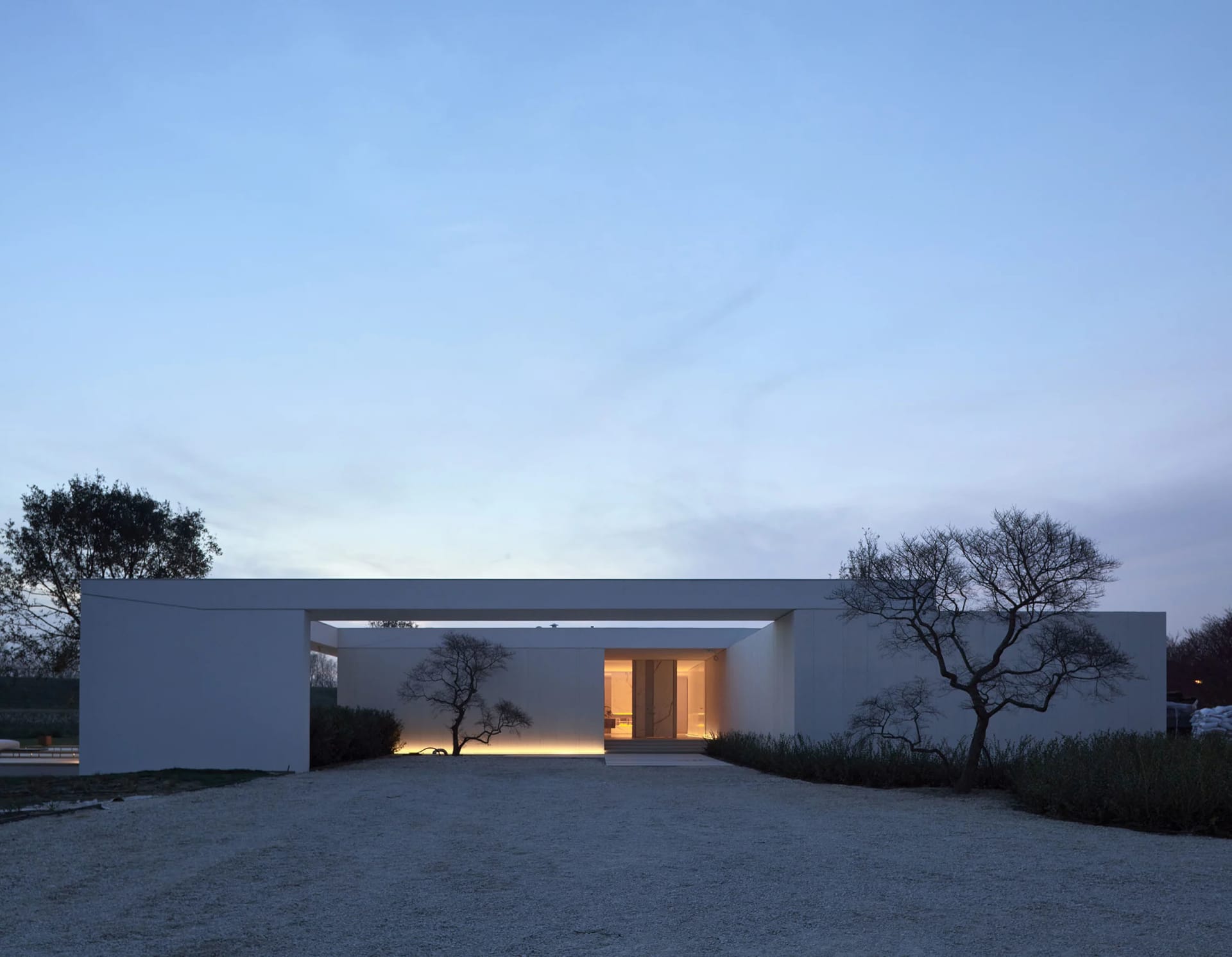 A minimalist concrete house with a modern design on a hillside.